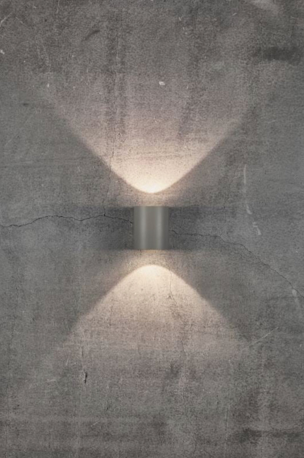 Wall-mounted light fixture casting a shadow on a textured wall