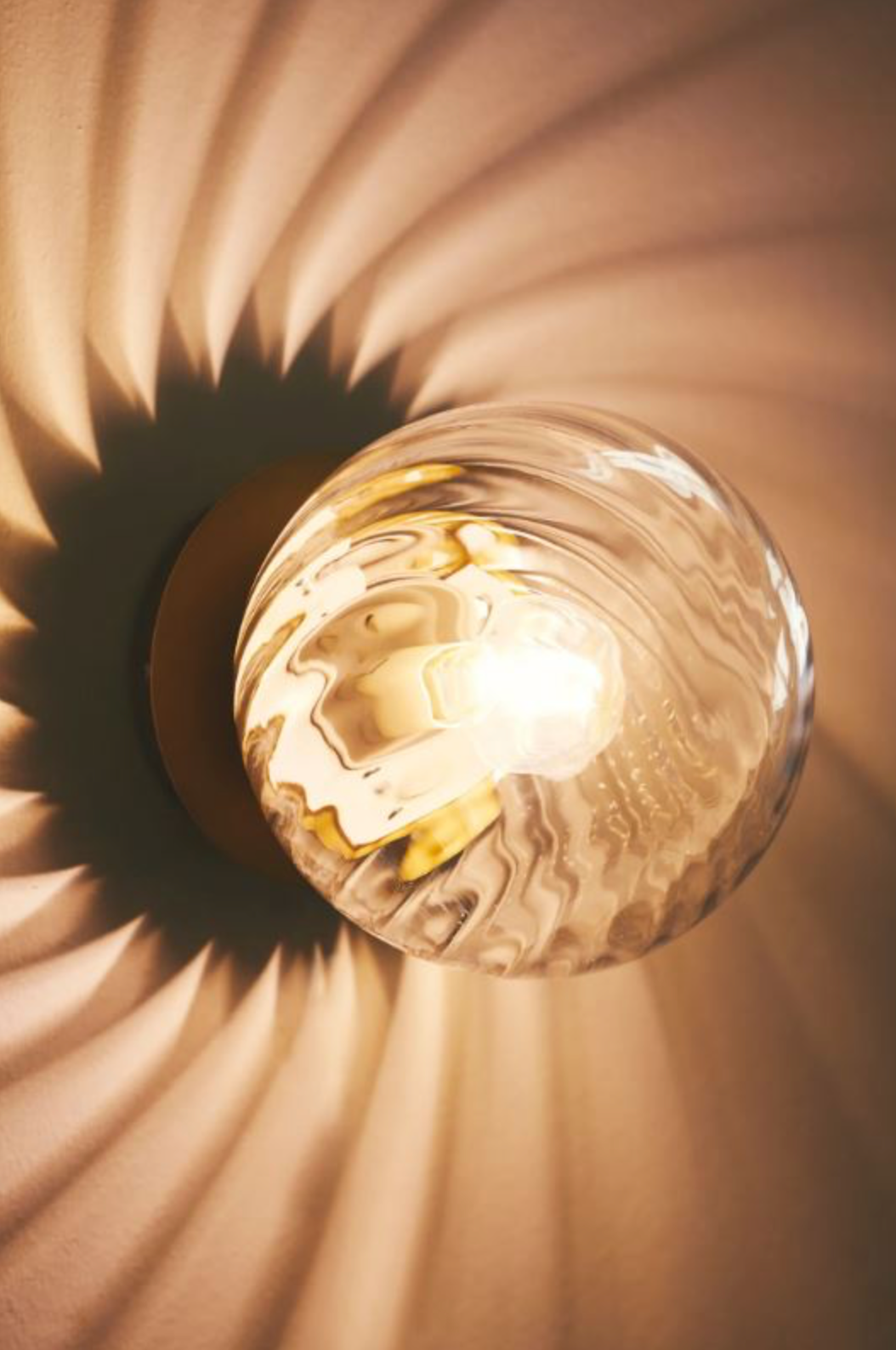 Light fixture casting a warm glow with a textured wall background