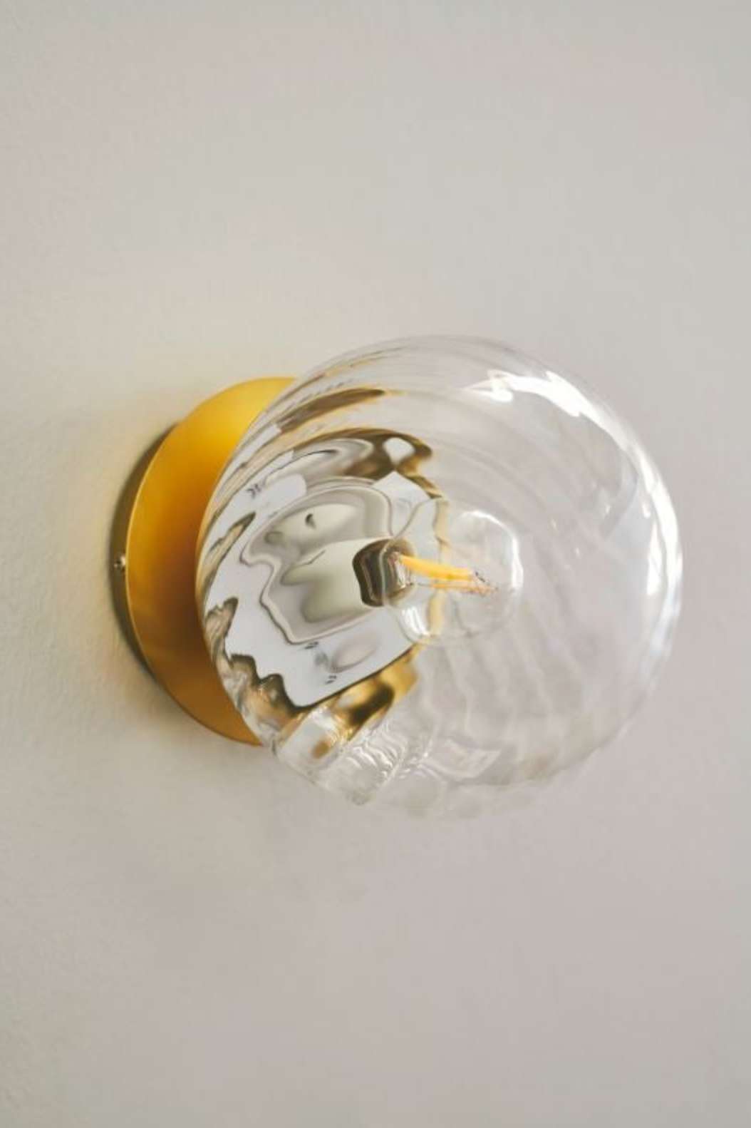 Clear glass light bulb with gold base on a white background