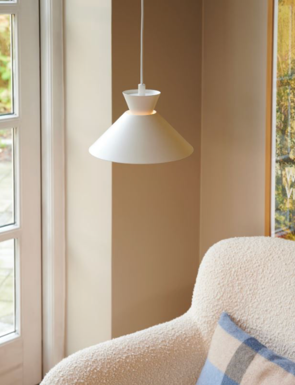 White pendant light hanging above a textured chair with a striped pillow.