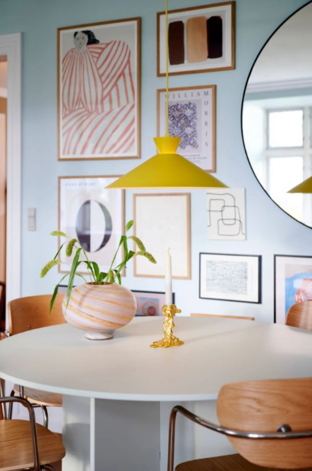 Dining room with round table, chairs, and wall art in a home setting.