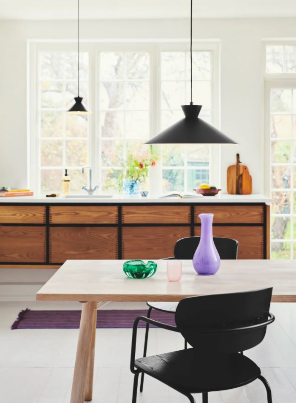 Modern kitchen with wooden cabinets, a dining table, and decorative vases.