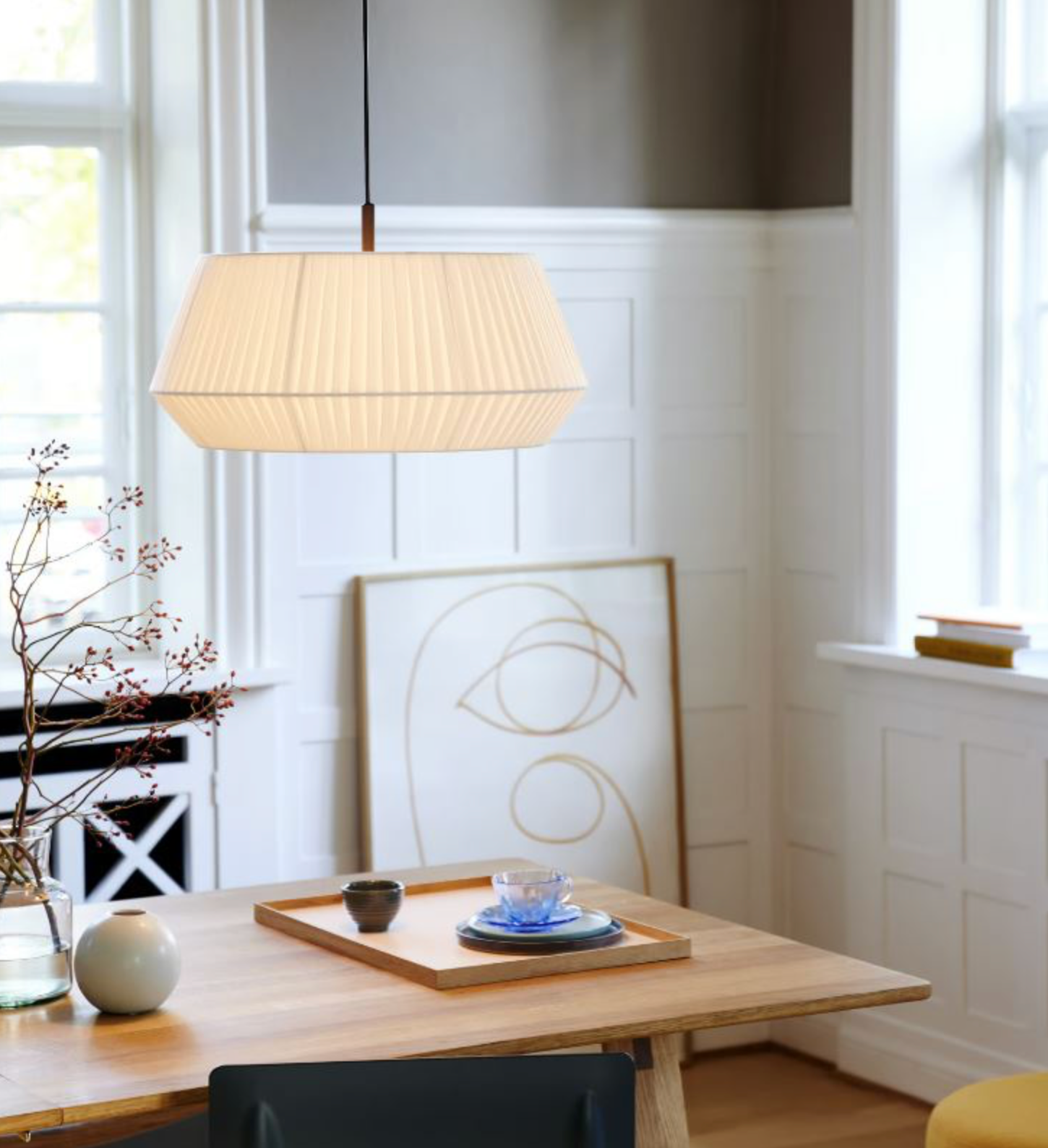 Modern interior with a fabric pendant light, wooden table, and abstract wall art.
