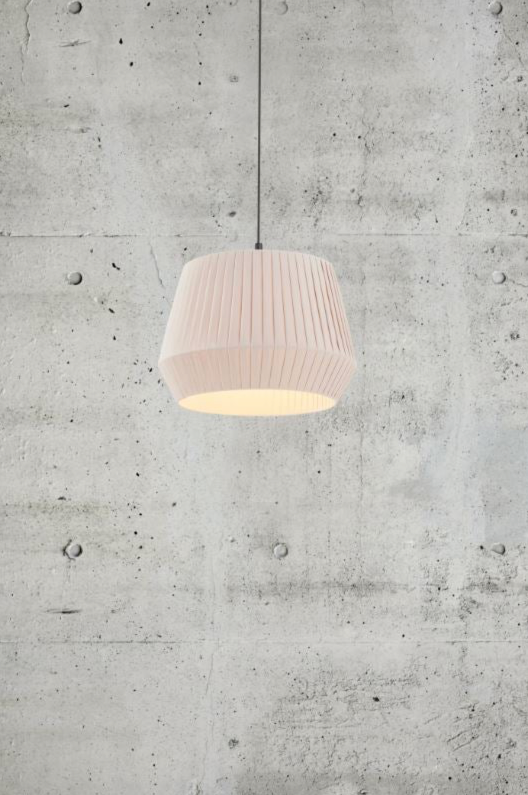 Beige fabric pendant light hanging against a concrete wall