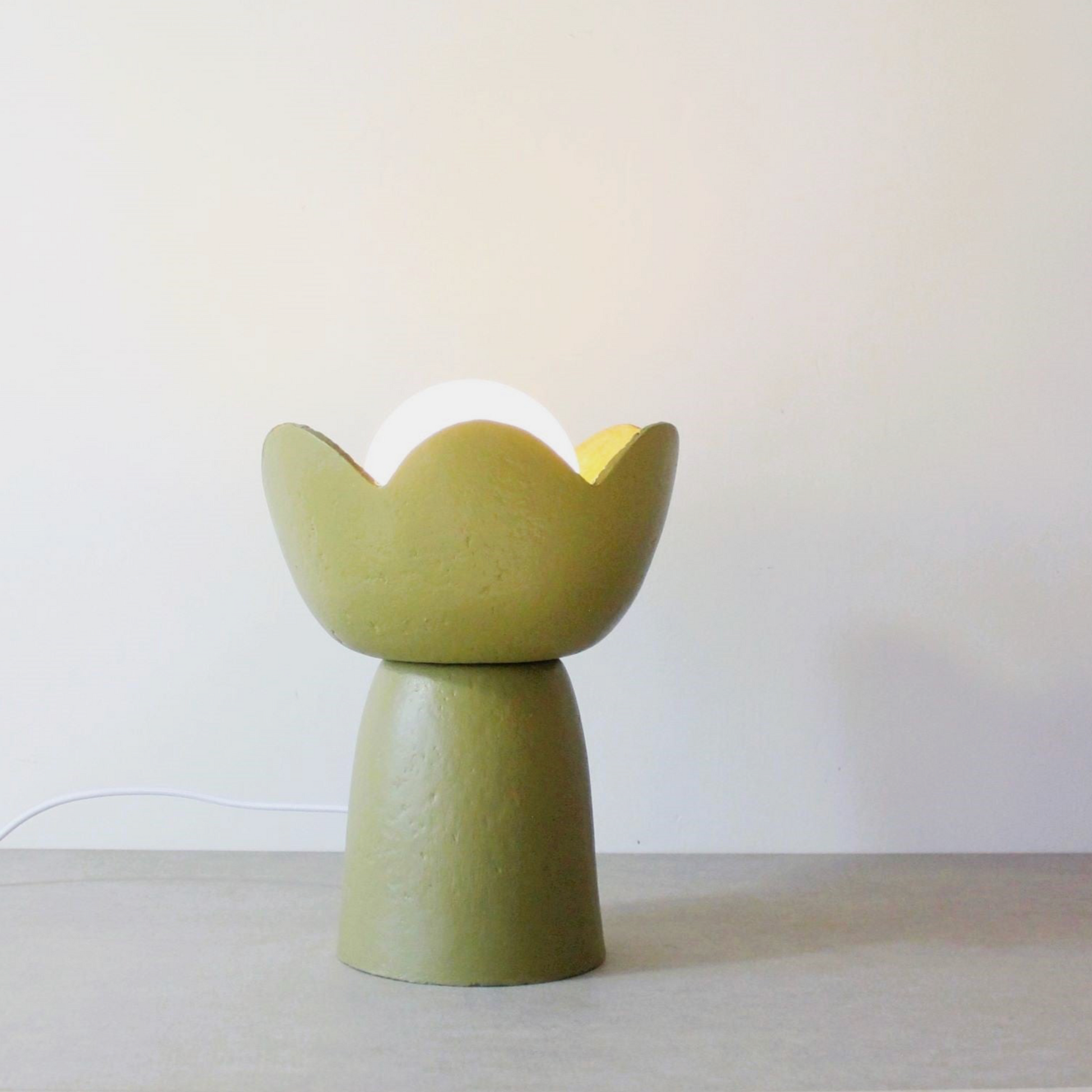Green ceramic lamp with white base on a light gray surface
