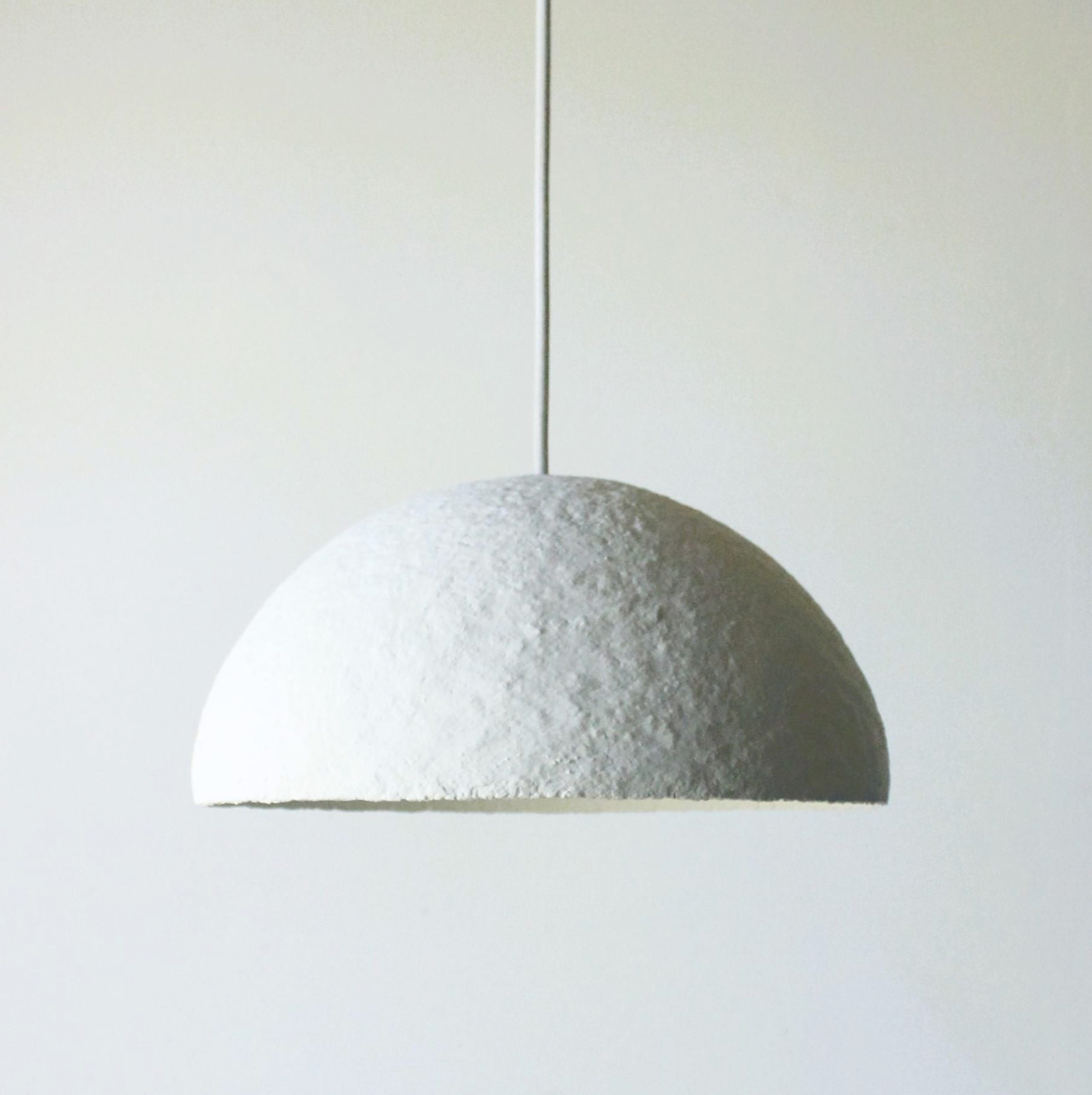 Textured white hand made pendant light on a white background