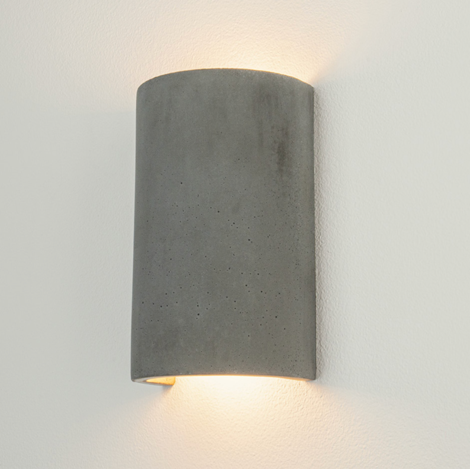 Cylindrical concrete wall light fixture on a plain background