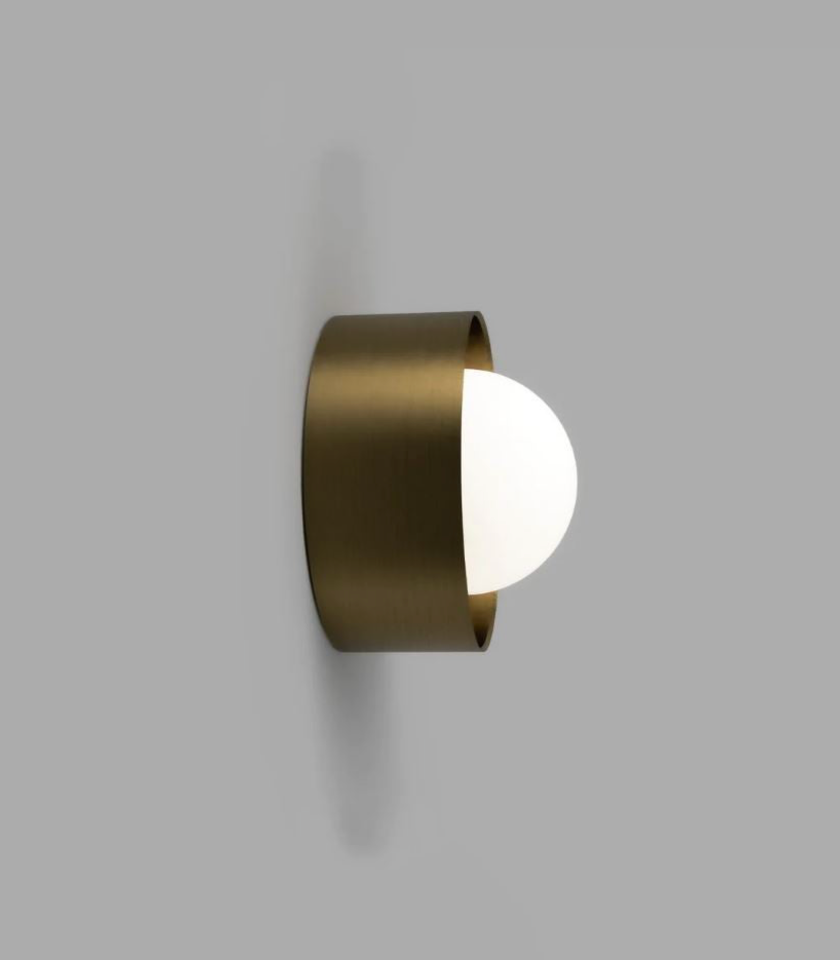 Wall-mounted light fixture with brass finish on a grey background