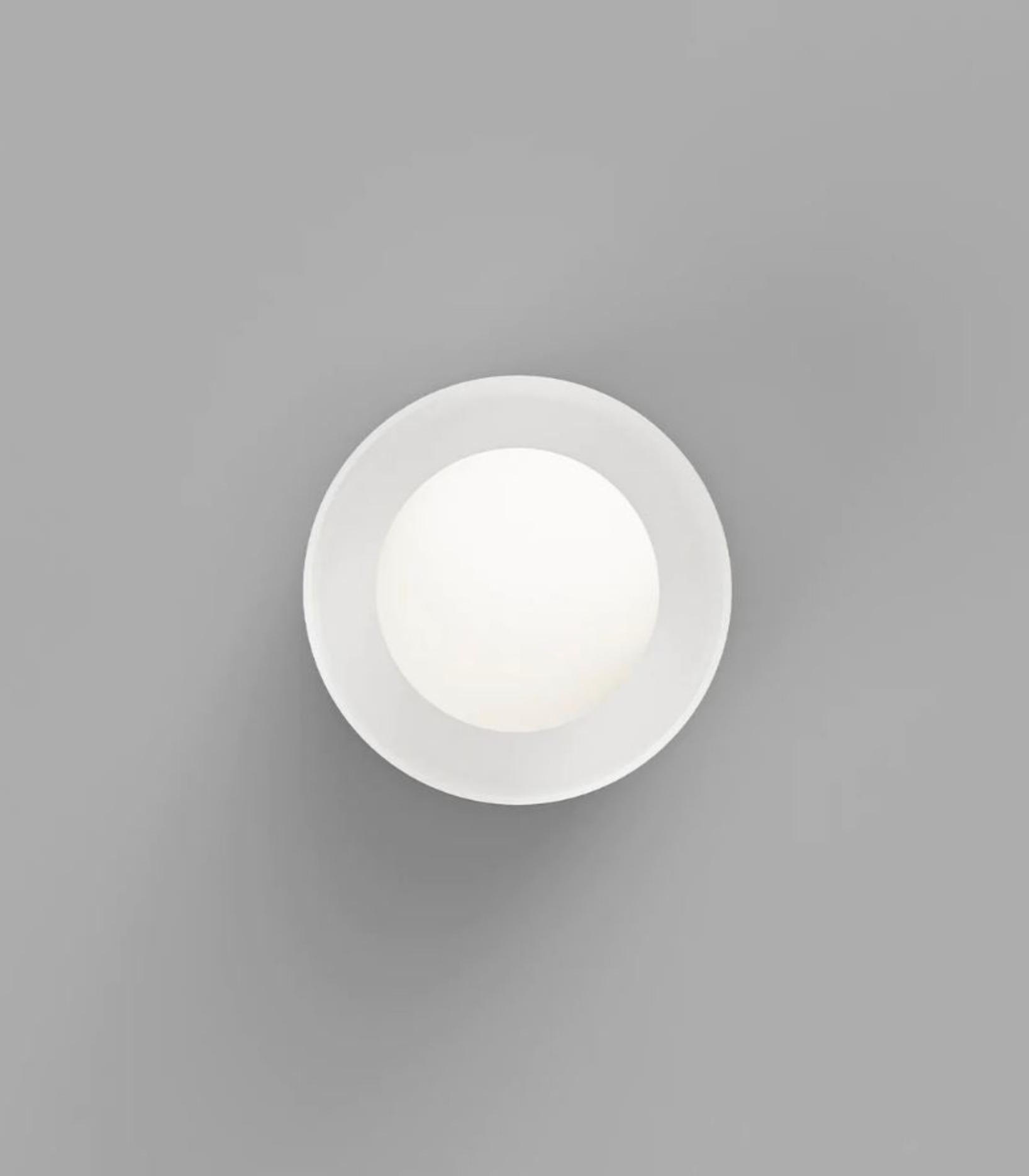 Round white light fixture on a grey background