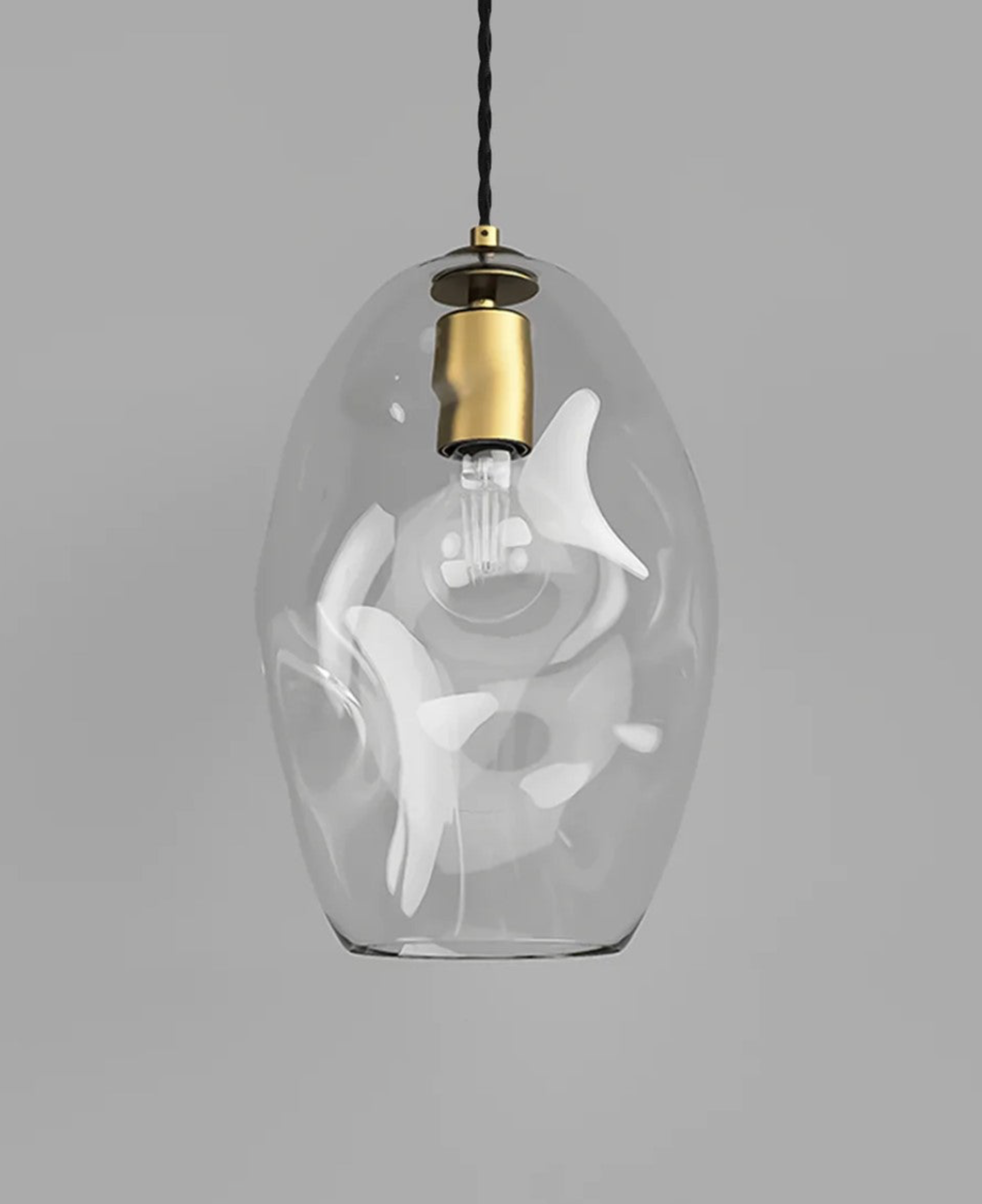 Clear glass pendant light with brass fixture on a gray background