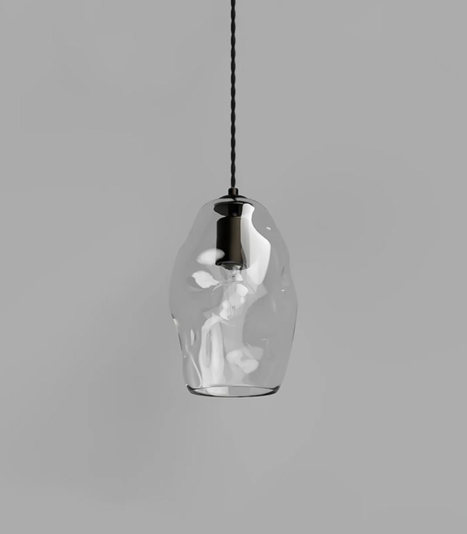 Clear glass pendant light with black cord on a gray background