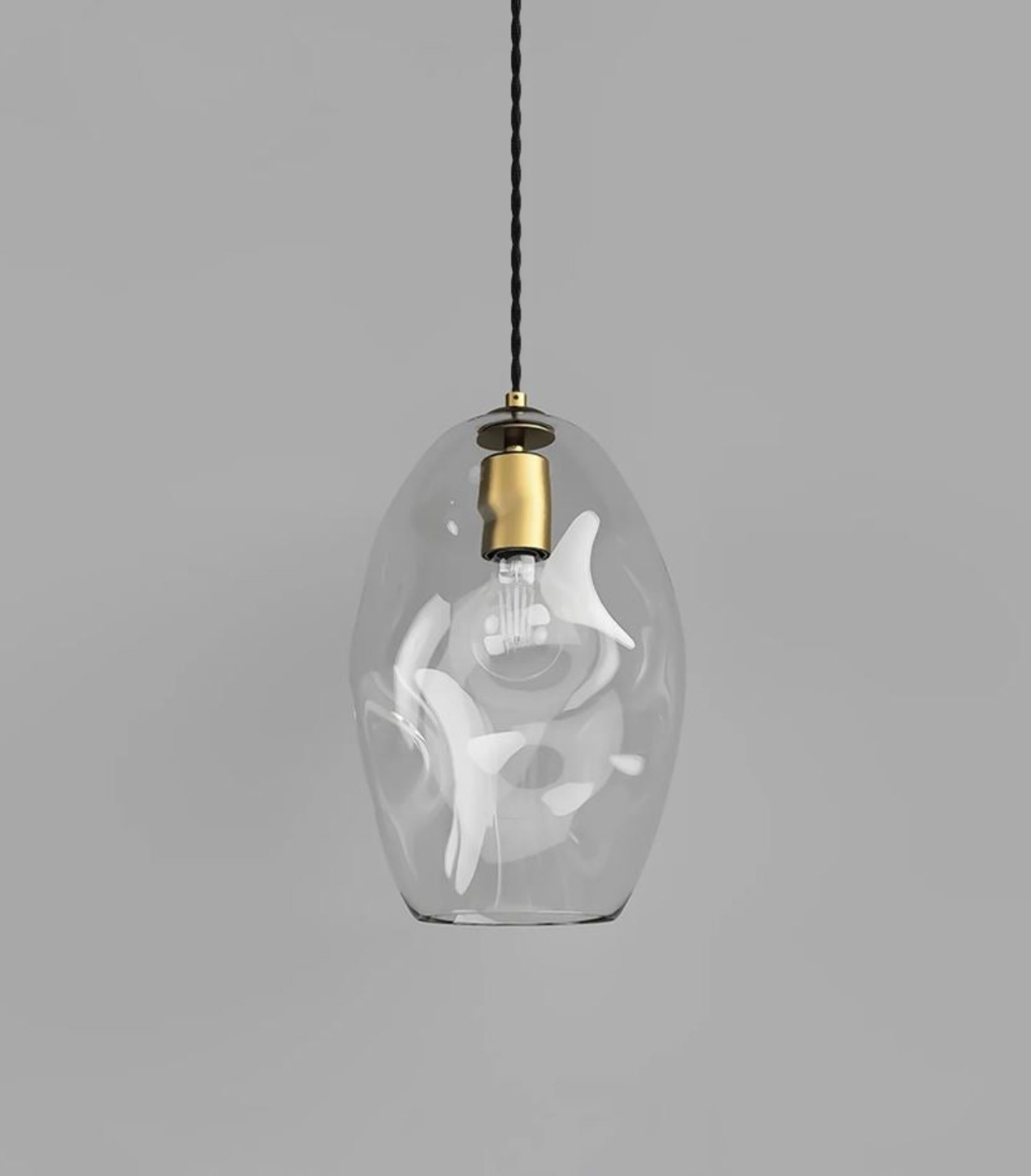 Clear glass pendant light with white abstract design on a gray background