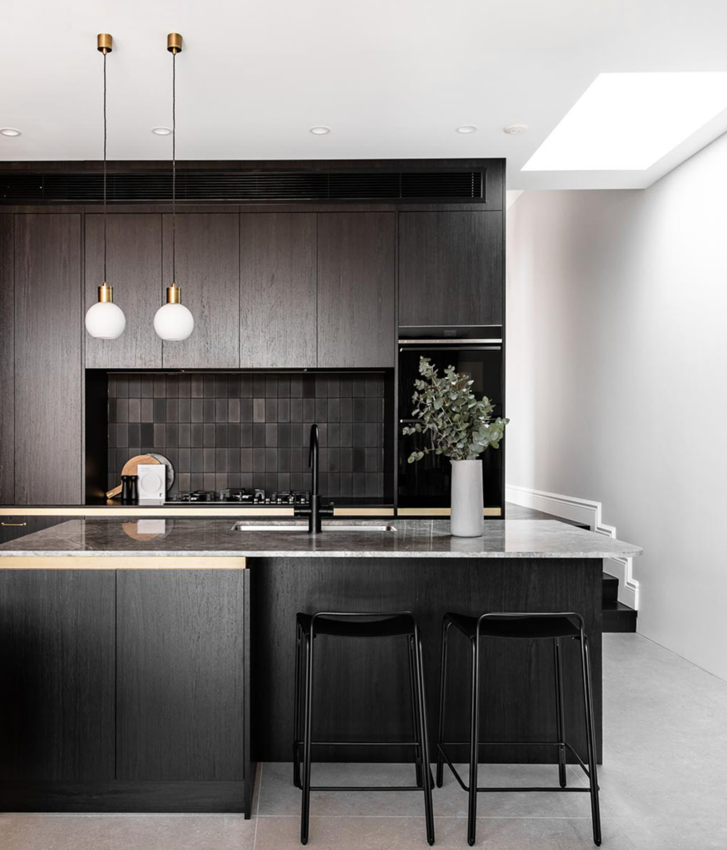 Modern kitchen with dark wood cabinets, black countertops, and white walls.