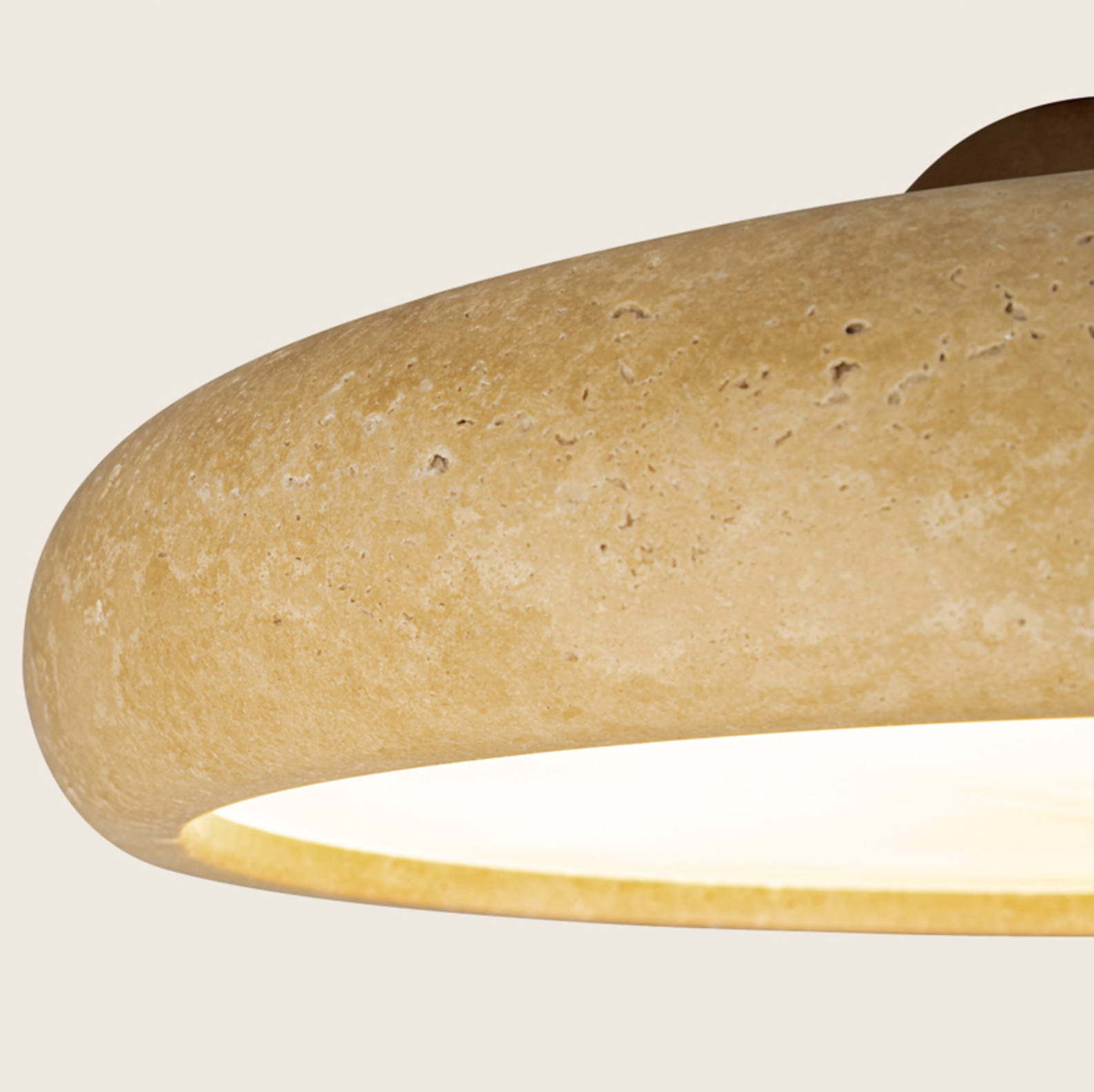 Close-up of a beige stone pendant light with a soft glow on a neutral background