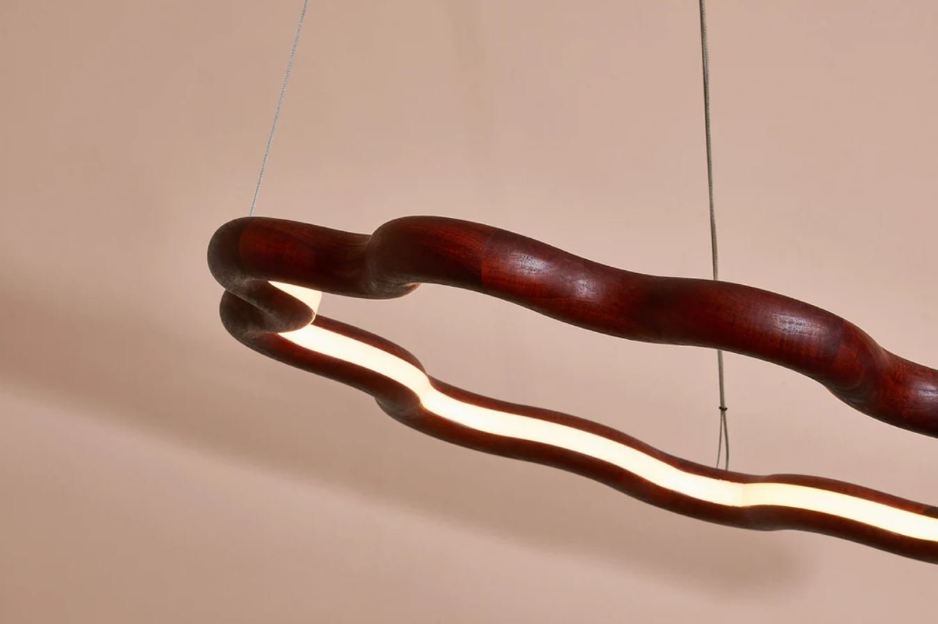 Modern hardwood pendant light with wavy design on a beige background