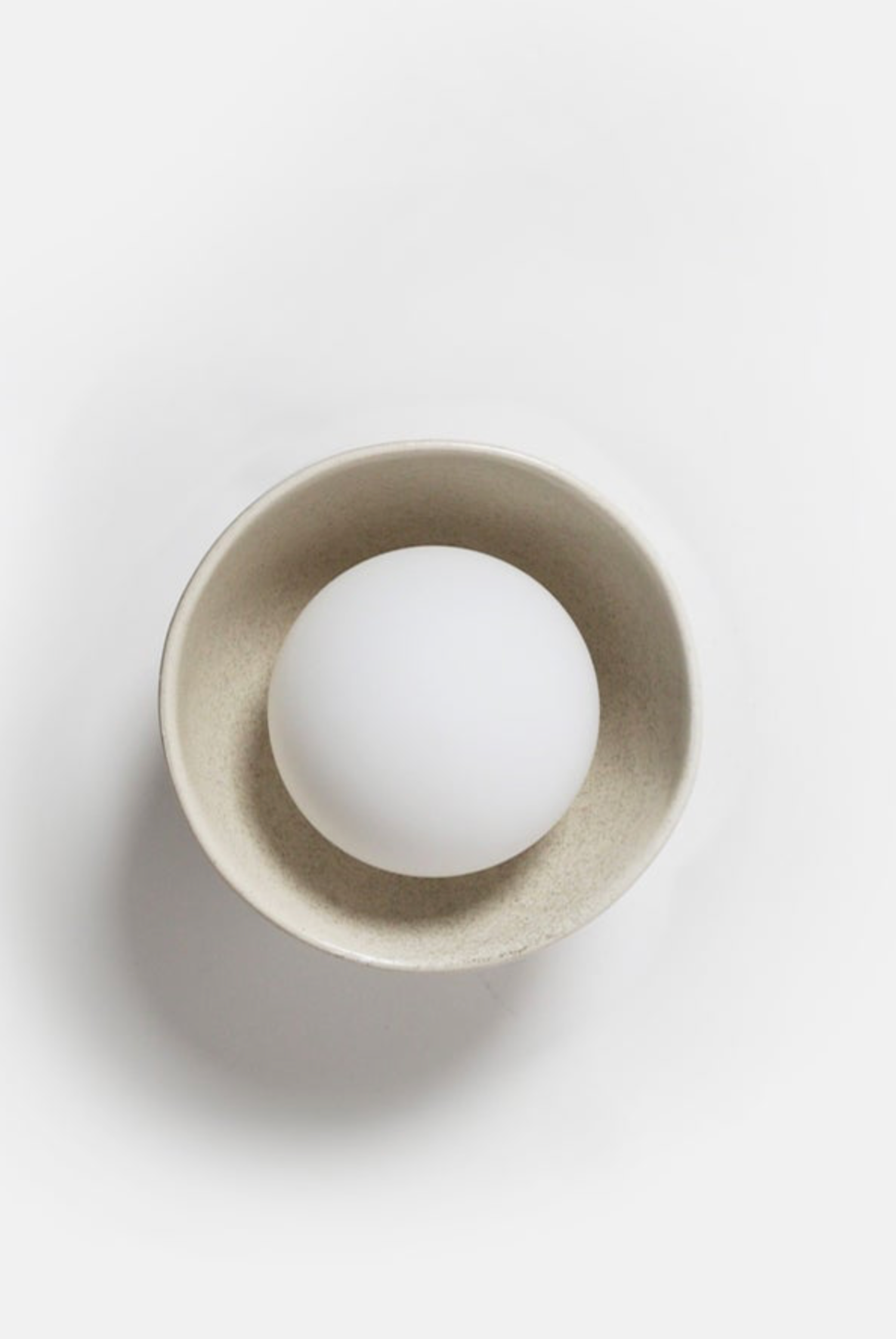 White sphere inside a beige circular container on a white background