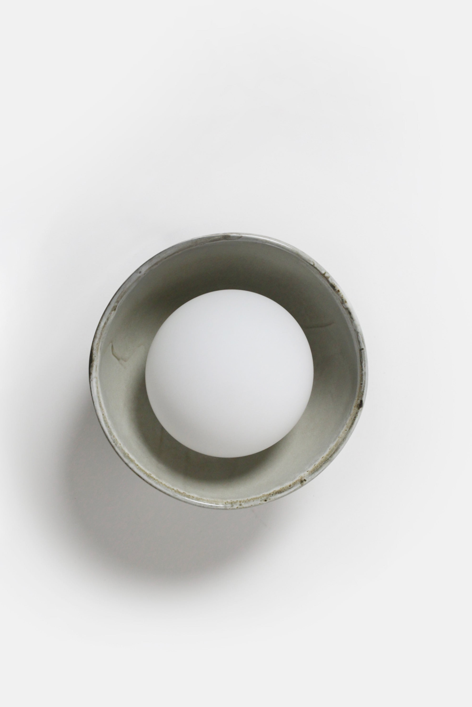 White sphere orb light inside a ceramic bowl on a white background