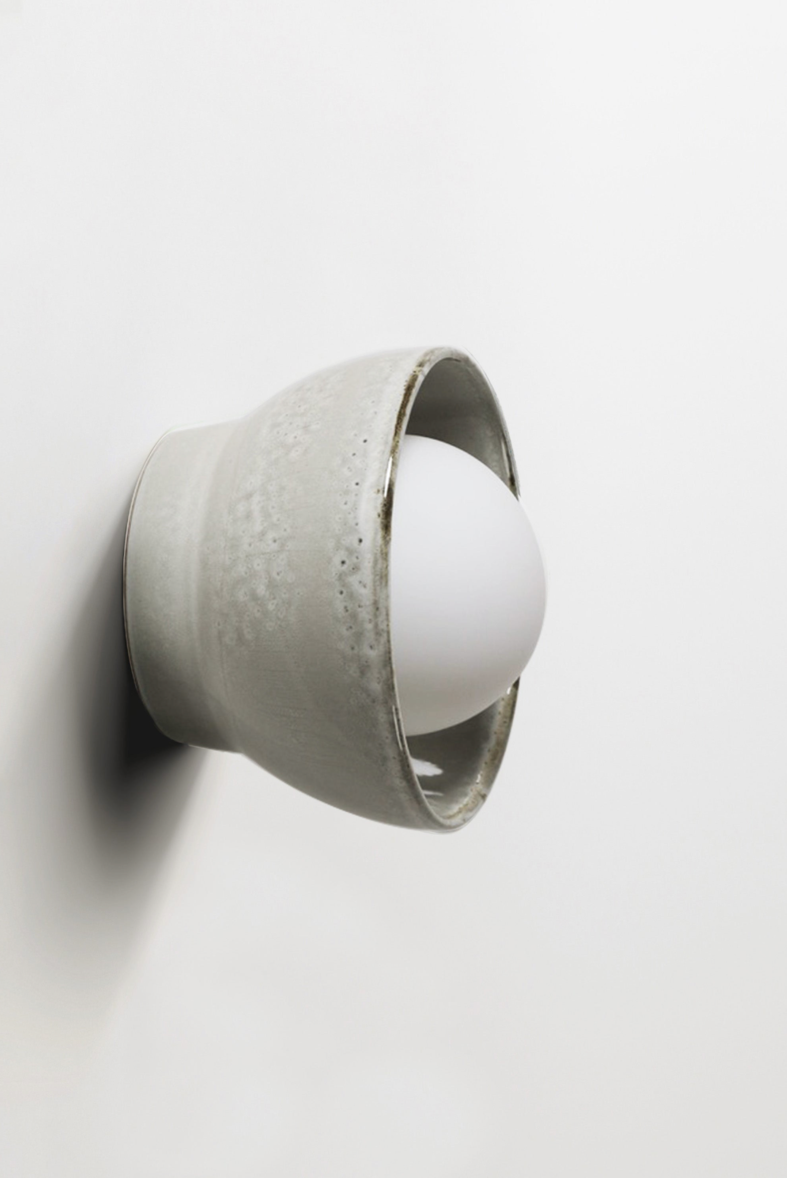 Ceramic wall sconce with a white bulb on a light gray background