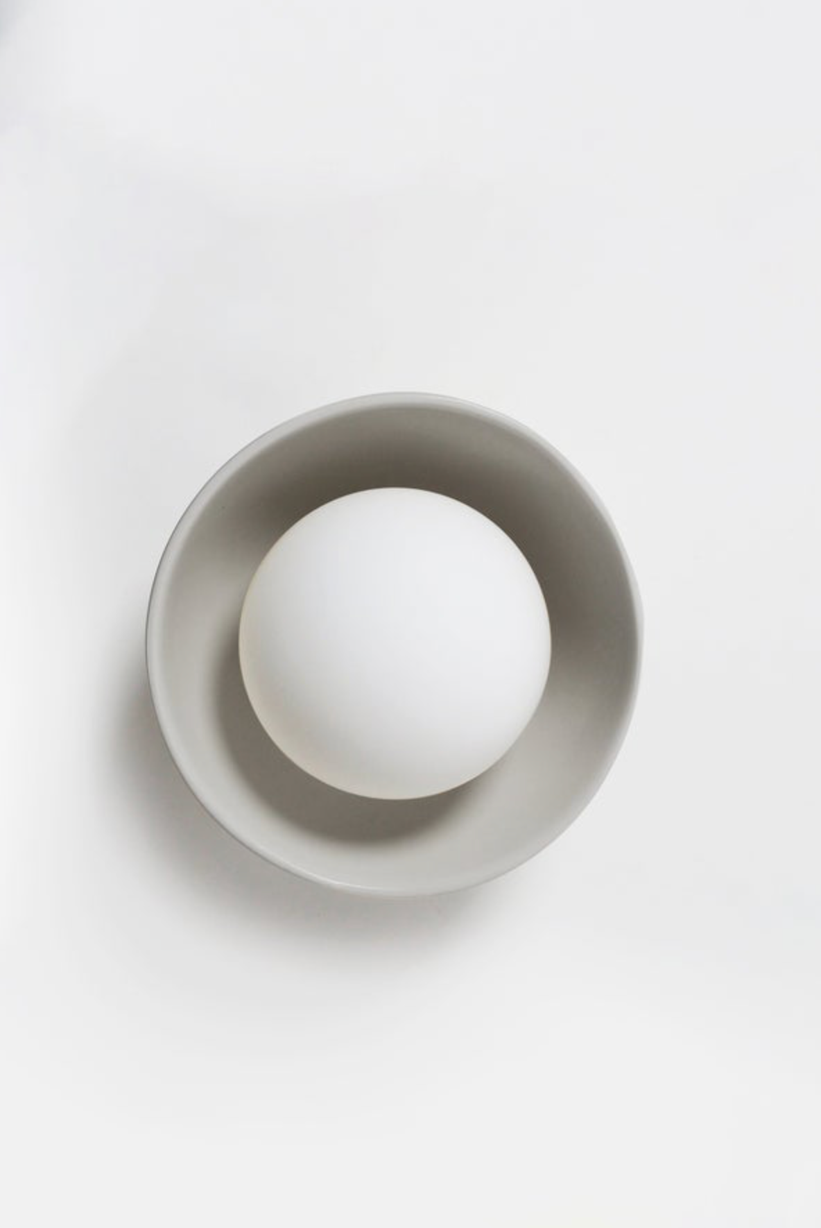 White sphere inside a gray bowl on a white background