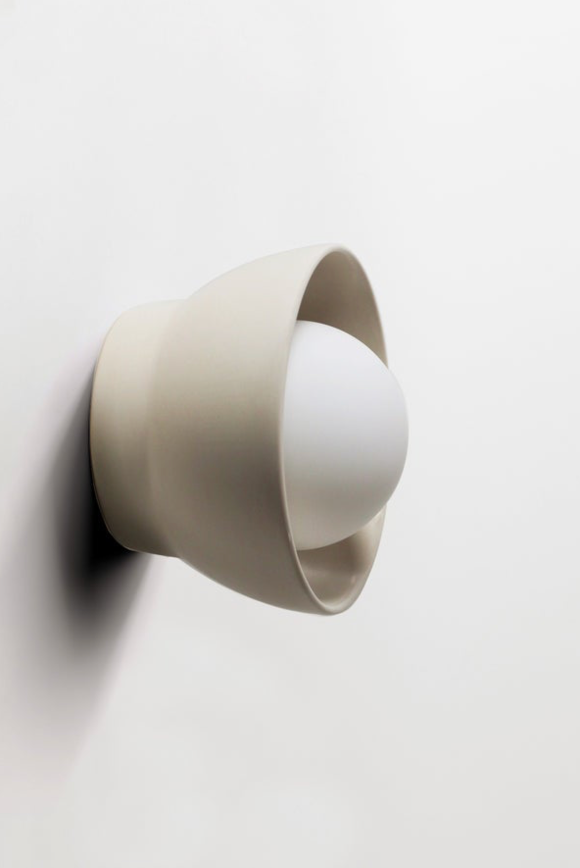 Wall-mounted light fixture with a beige ceramic on a white background