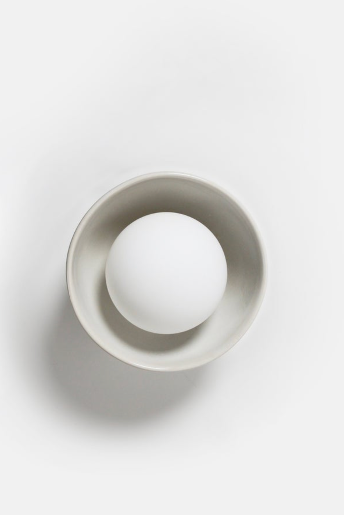 White sphere inside a gray circular container on a white background