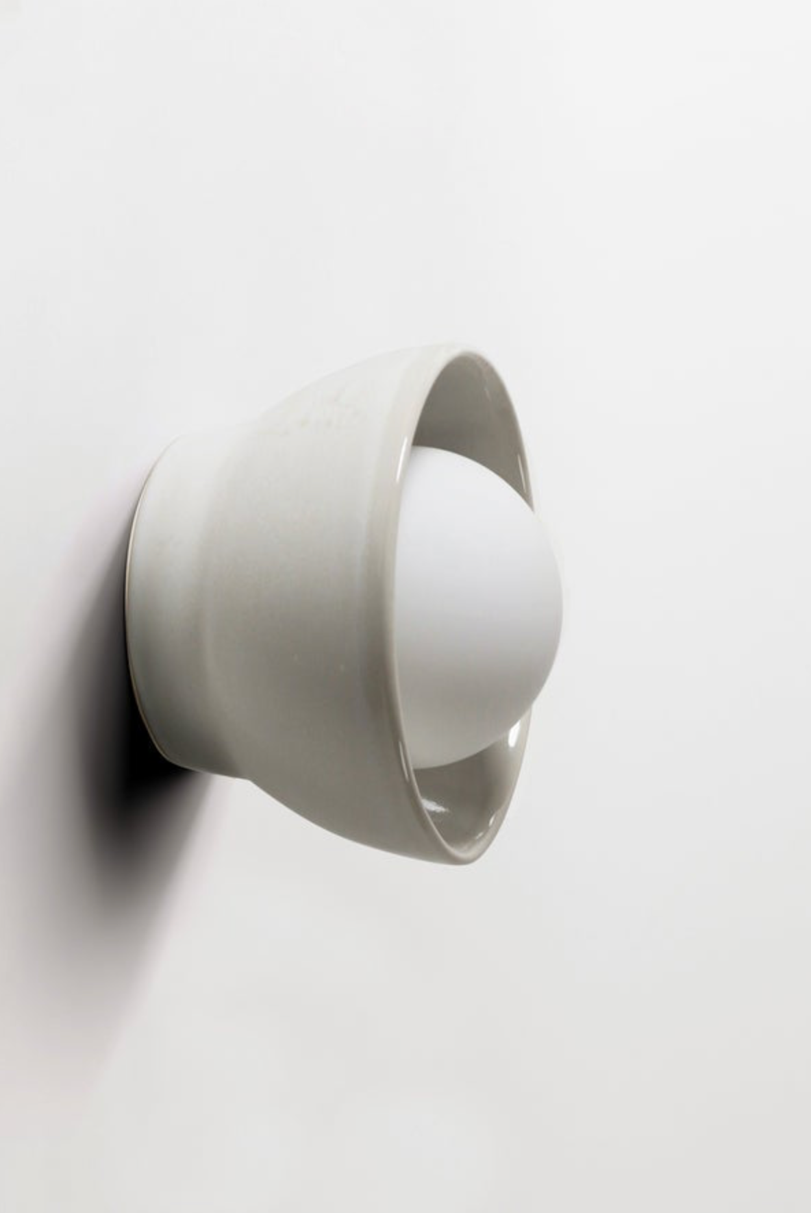 White wall-mounted light fixture on a white background