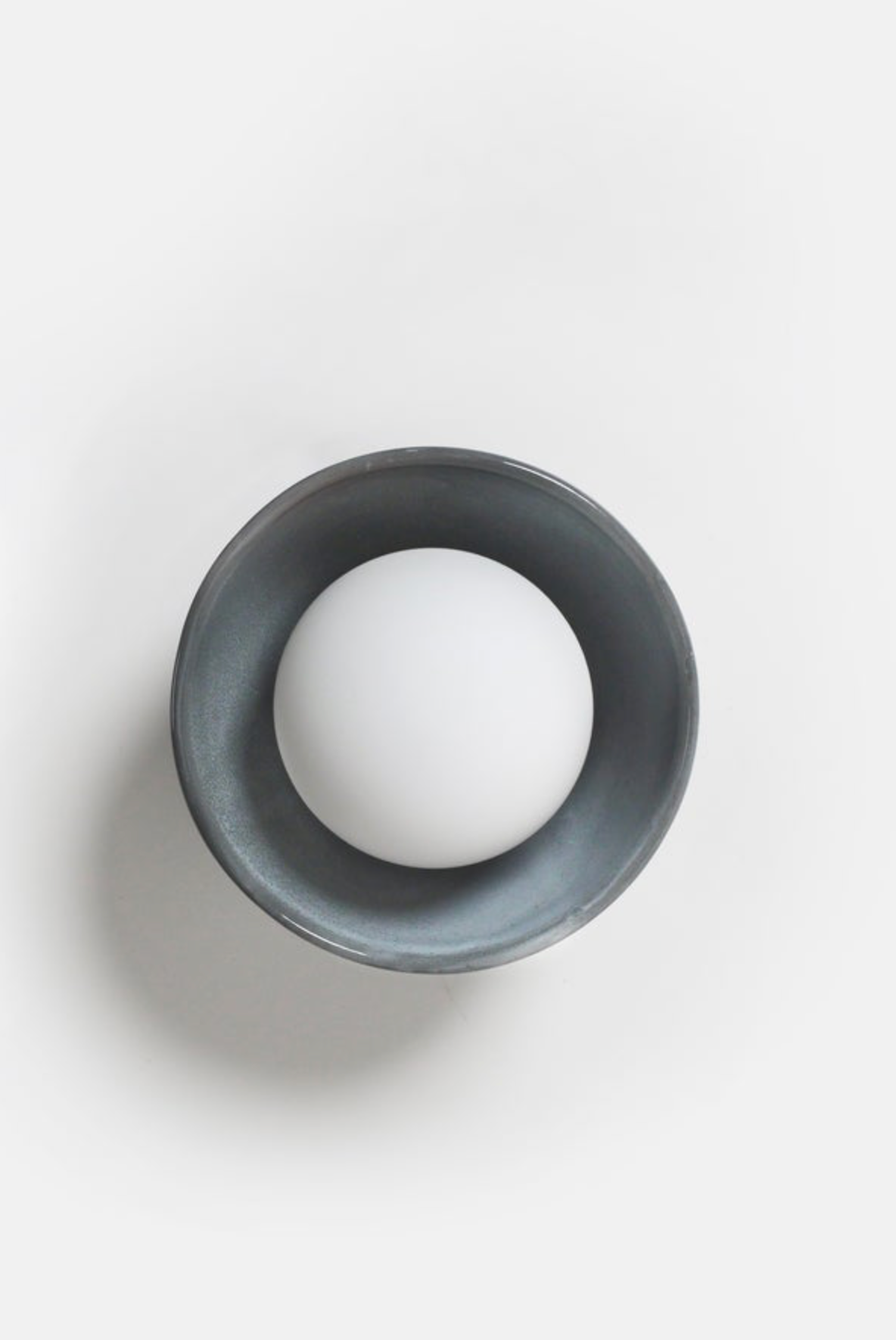 White orb light inside a dark ceramic bowl on a white background