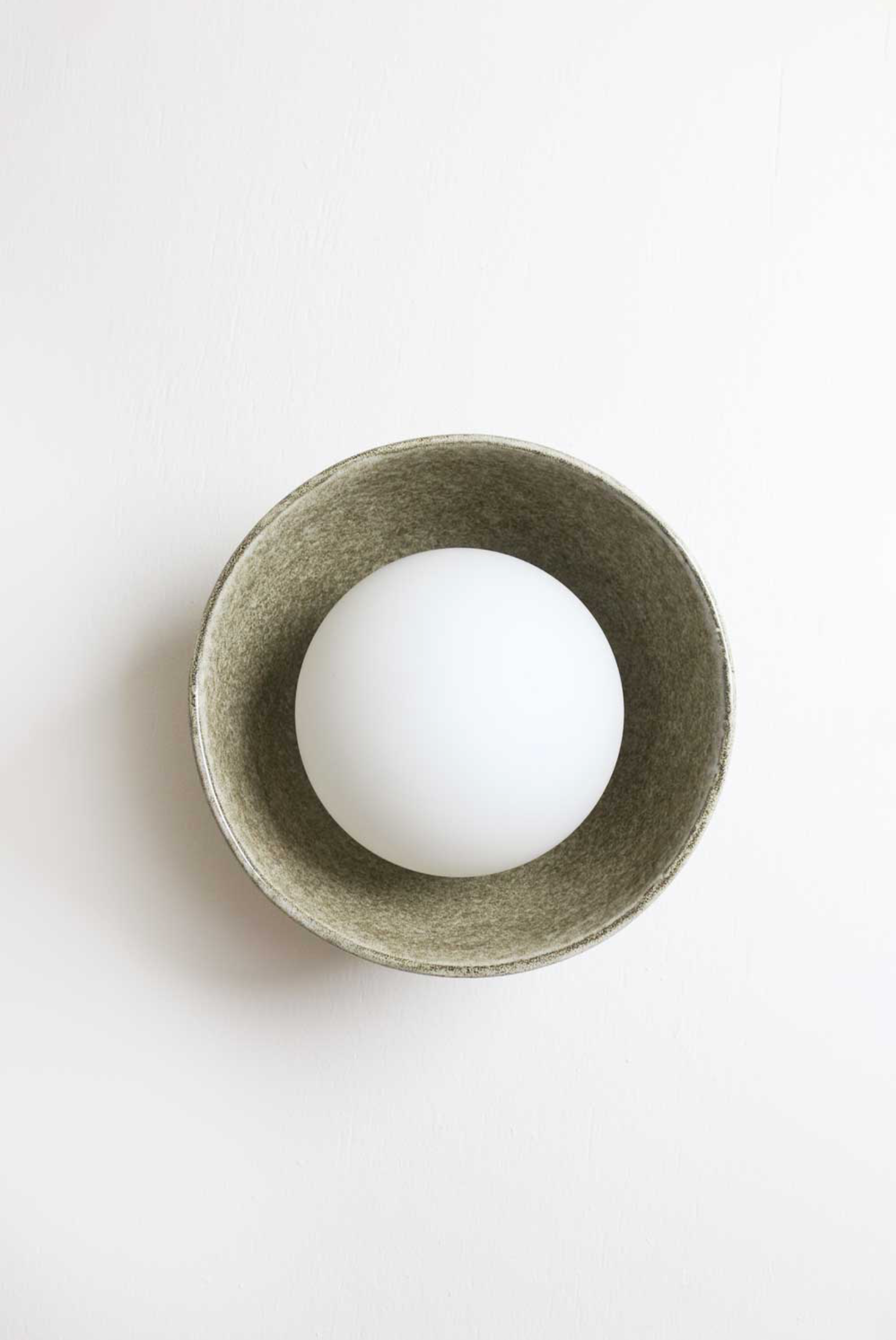 White interior orb light in a green ceramic bowl on a white background