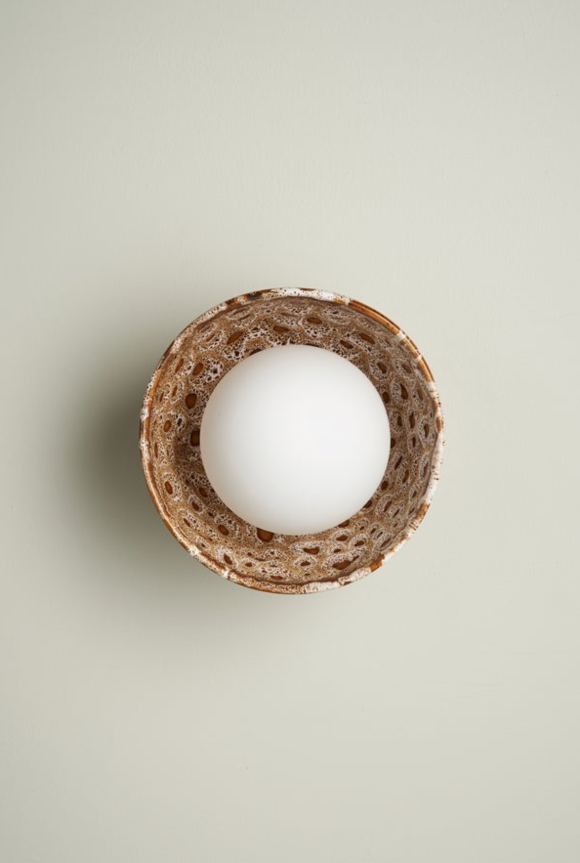 White interior orb wall light in a natural ceramic bowl on a light beige background