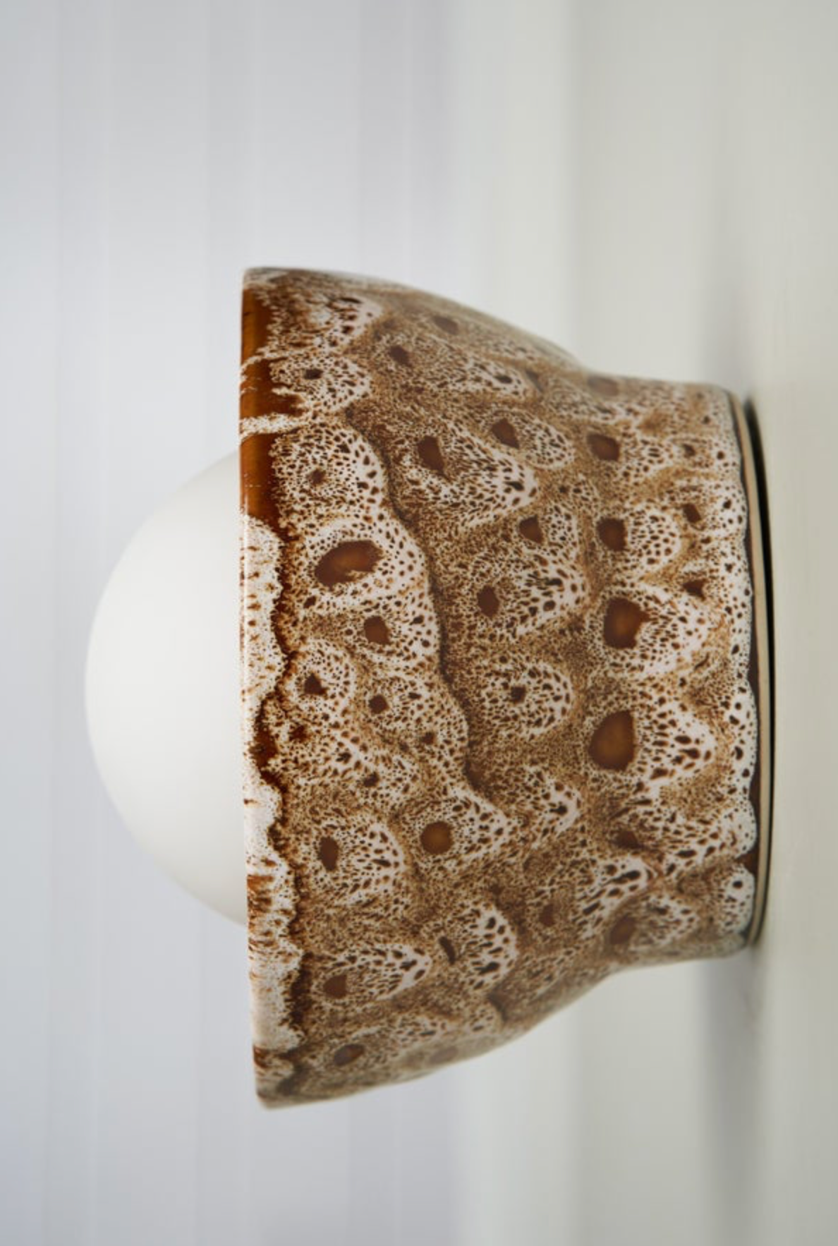 Ceramic wall light with brown and white glaze pattern on a white background