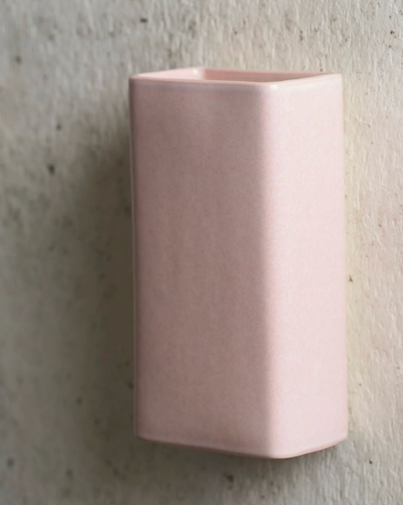 Rectangle pink ceramic wall sconce on a textured grey surface