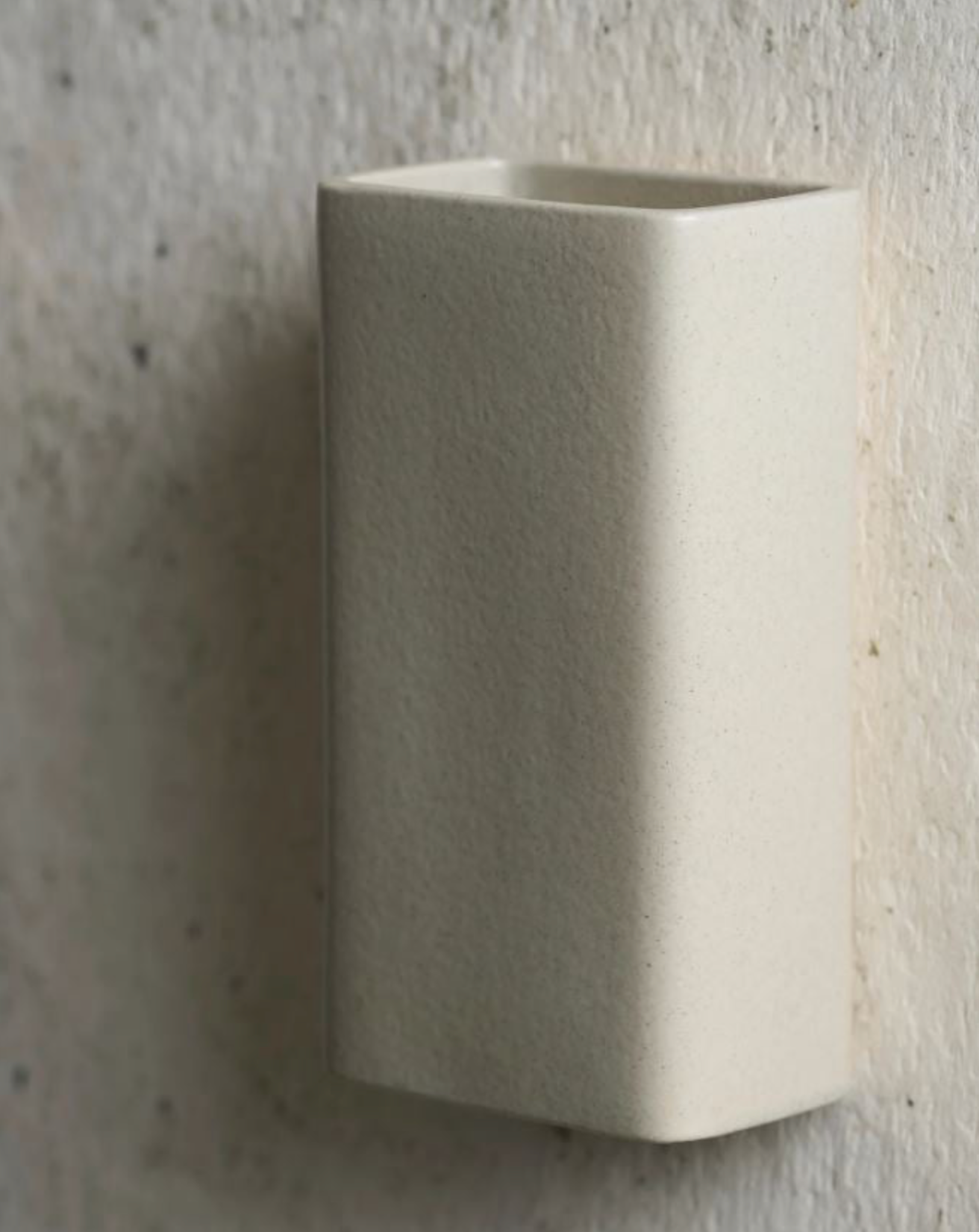 Hexagonal ceramic sconce against a textured wall