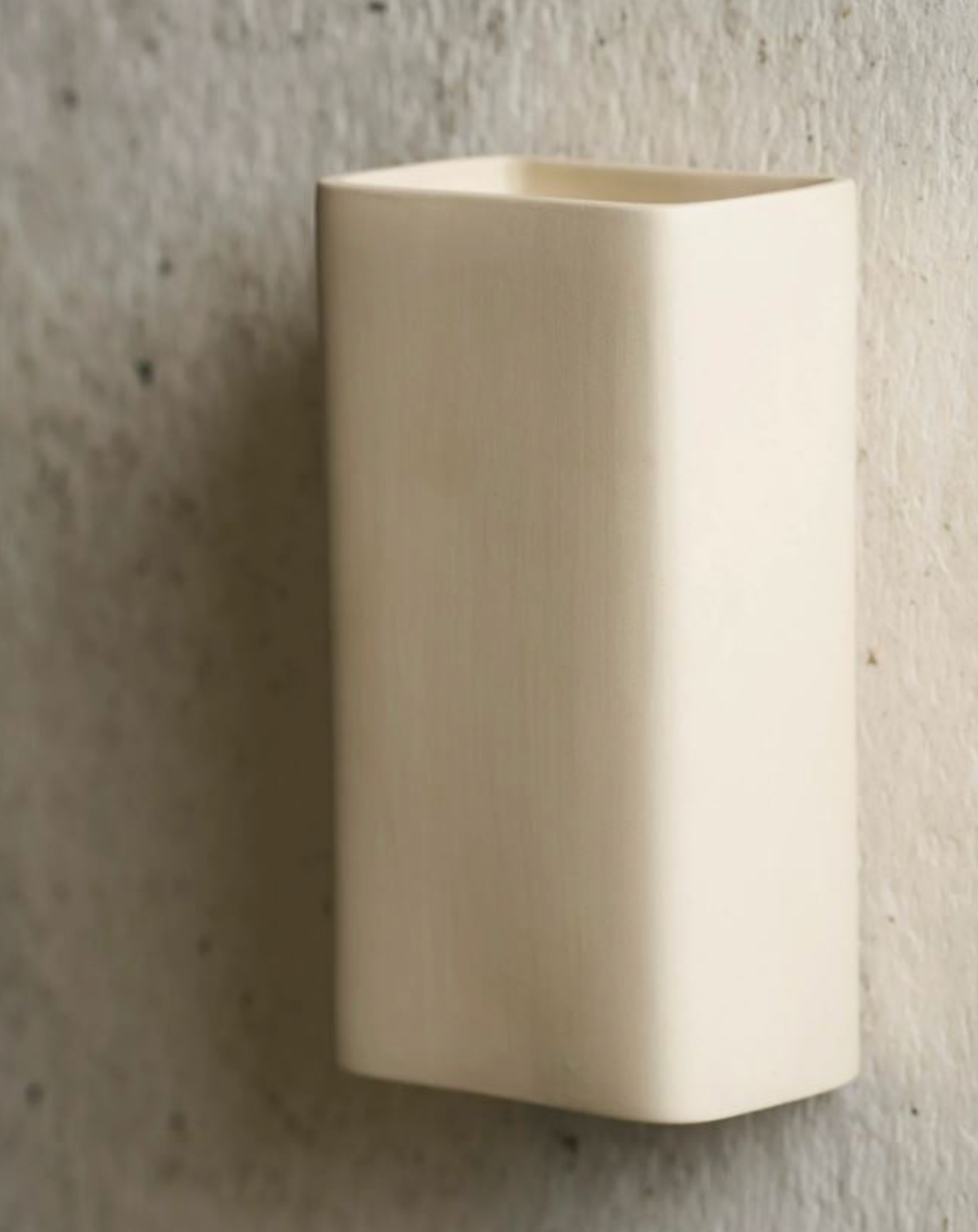 Beige wall-mounted light fixture on a textured wall