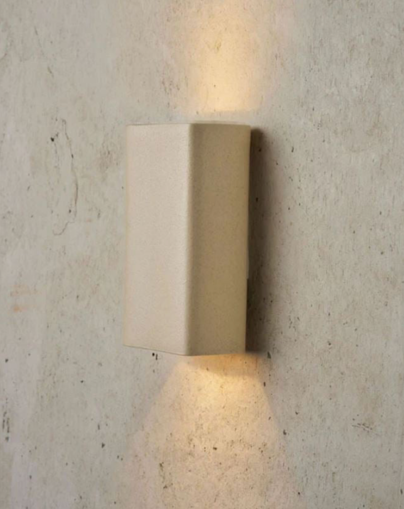 Beige wall-mounted outdoor light fixture on a textured concrete wall.