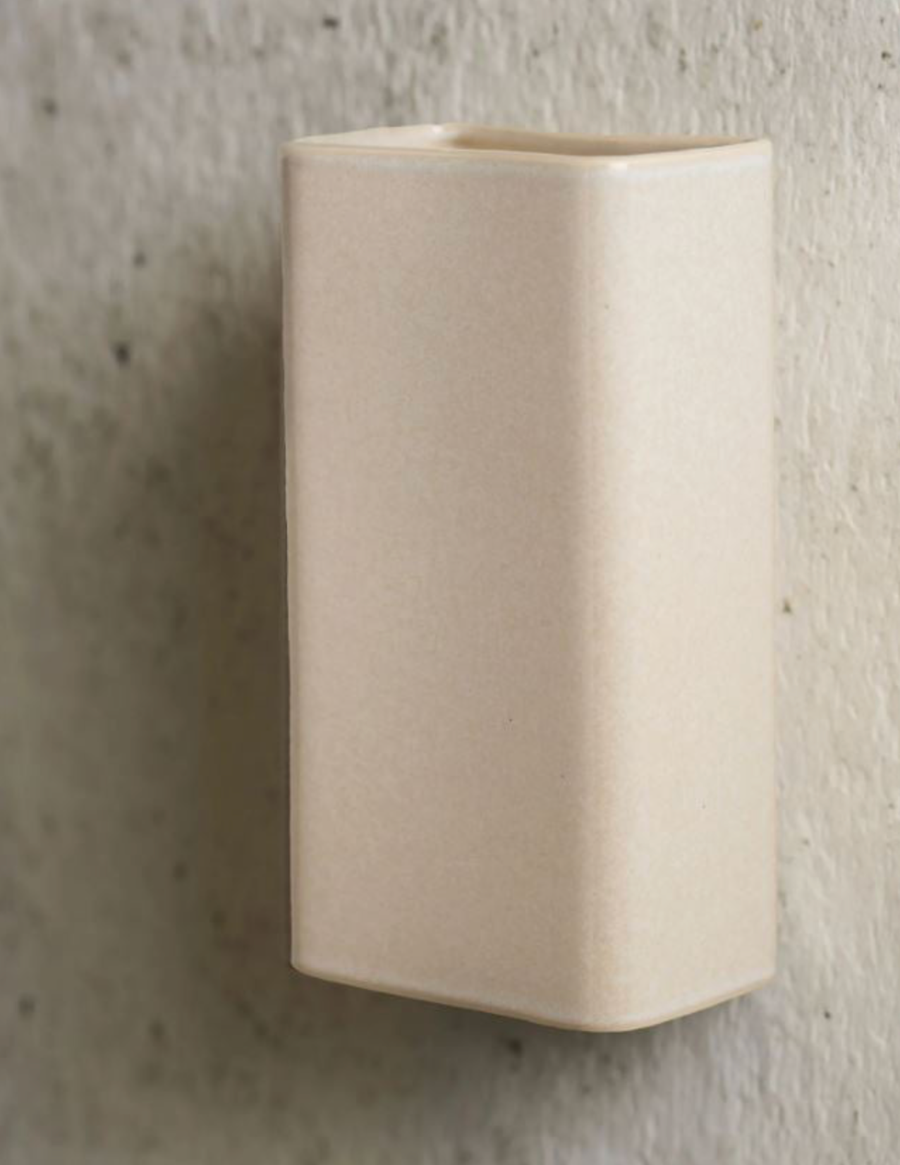 Beige ceramic wall light on a textured gray background