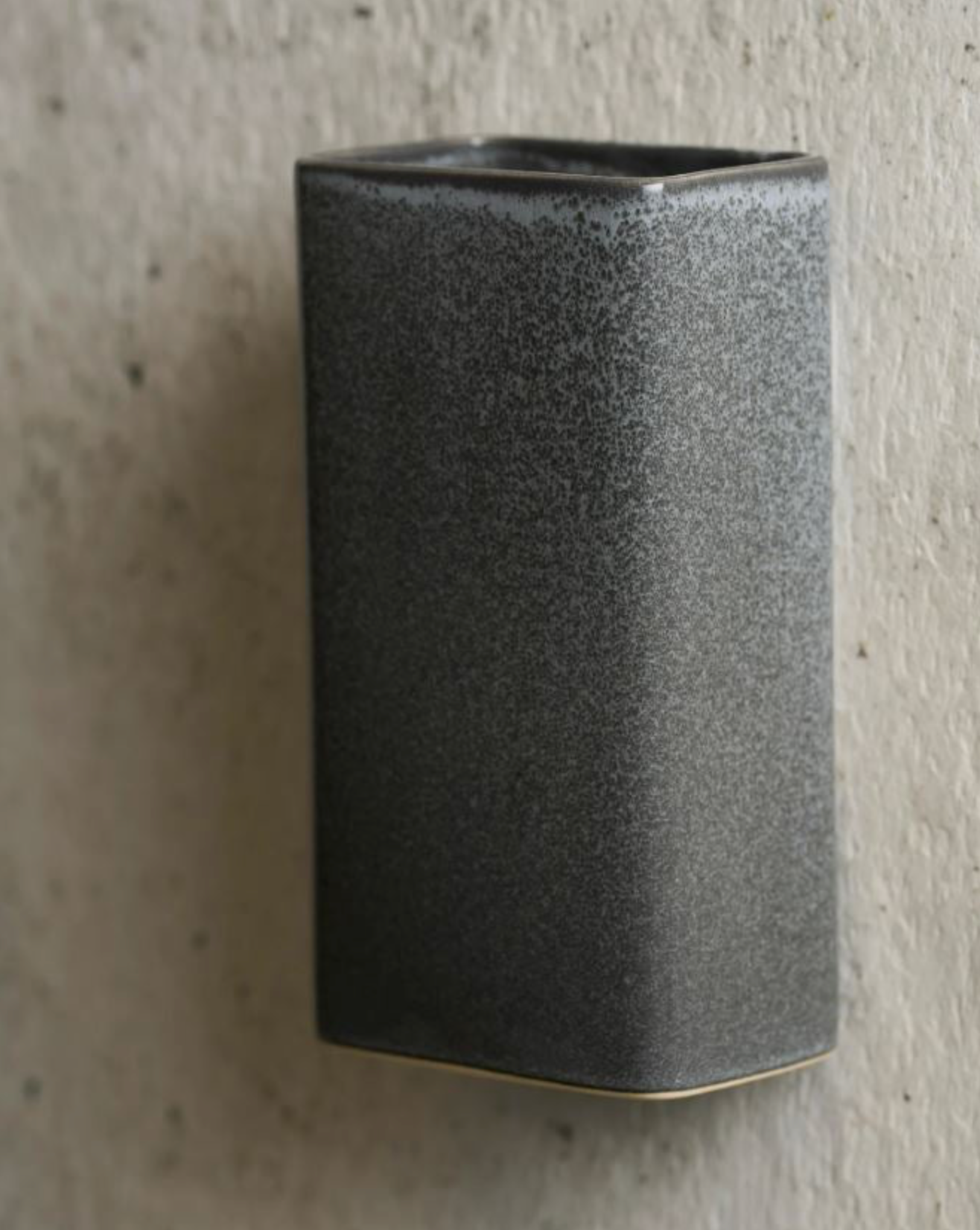 Textured black ceramic wall light on a concrete surface