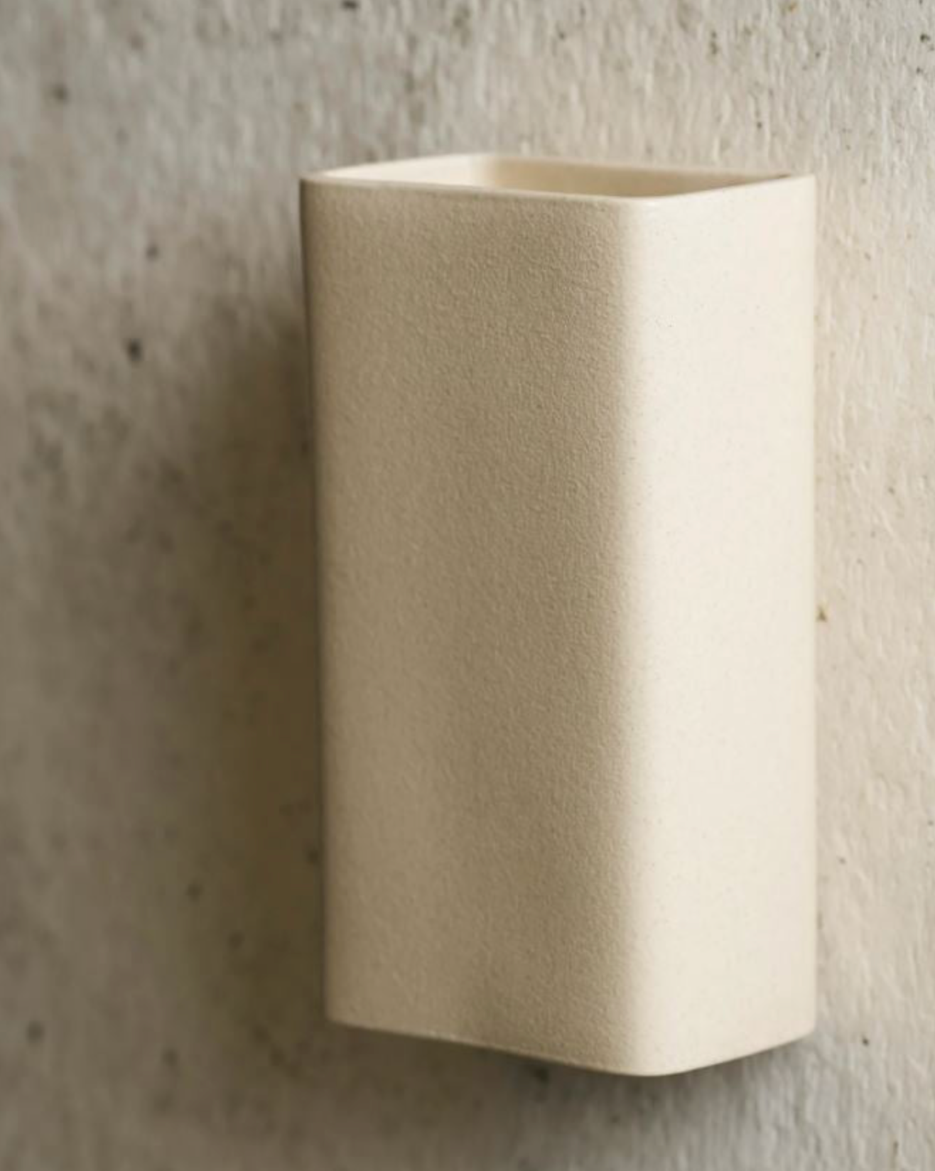Beige wall-mounted light against a textured grey wall