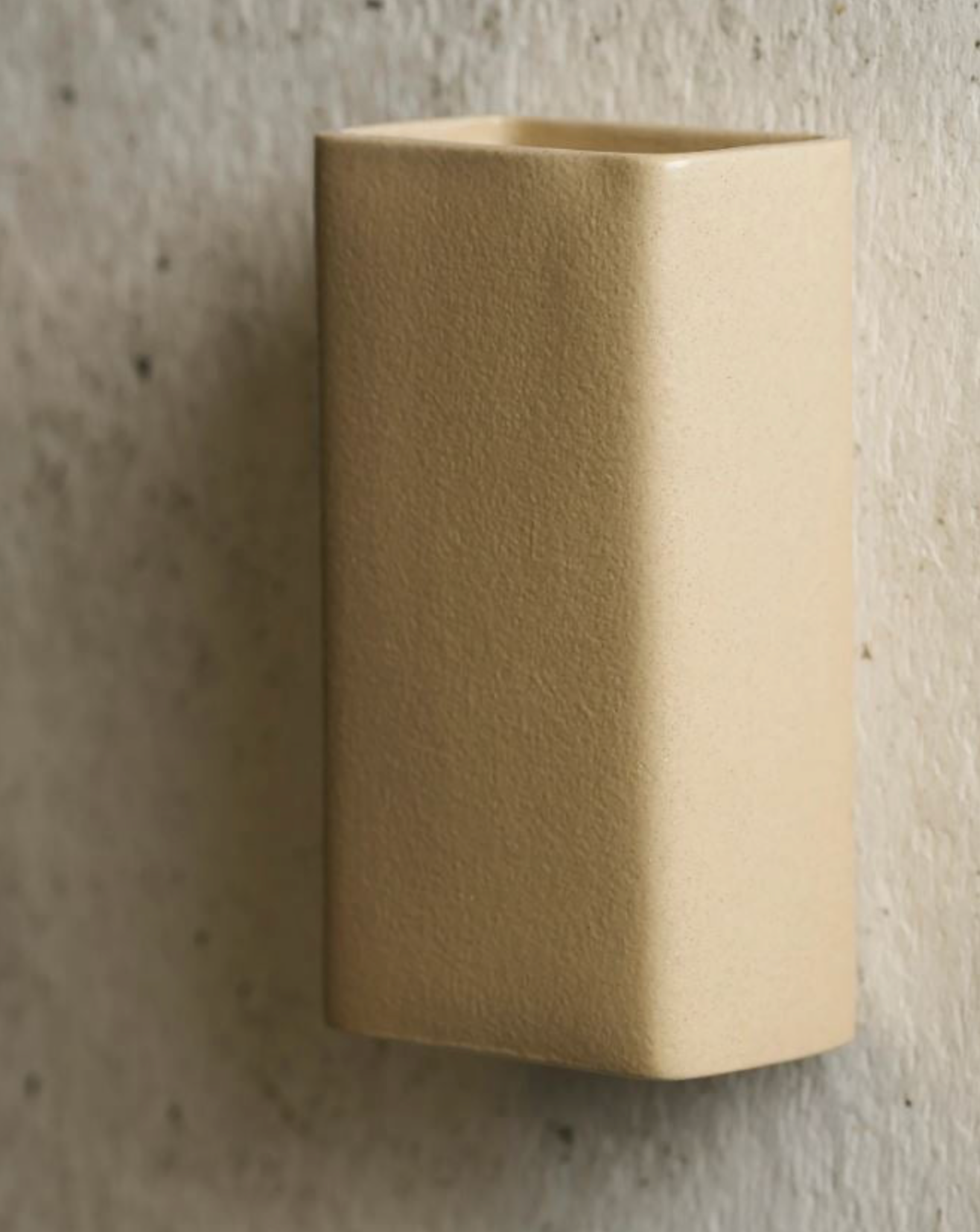 Beige rectangular wall-mounted light fixture on a textured wall.