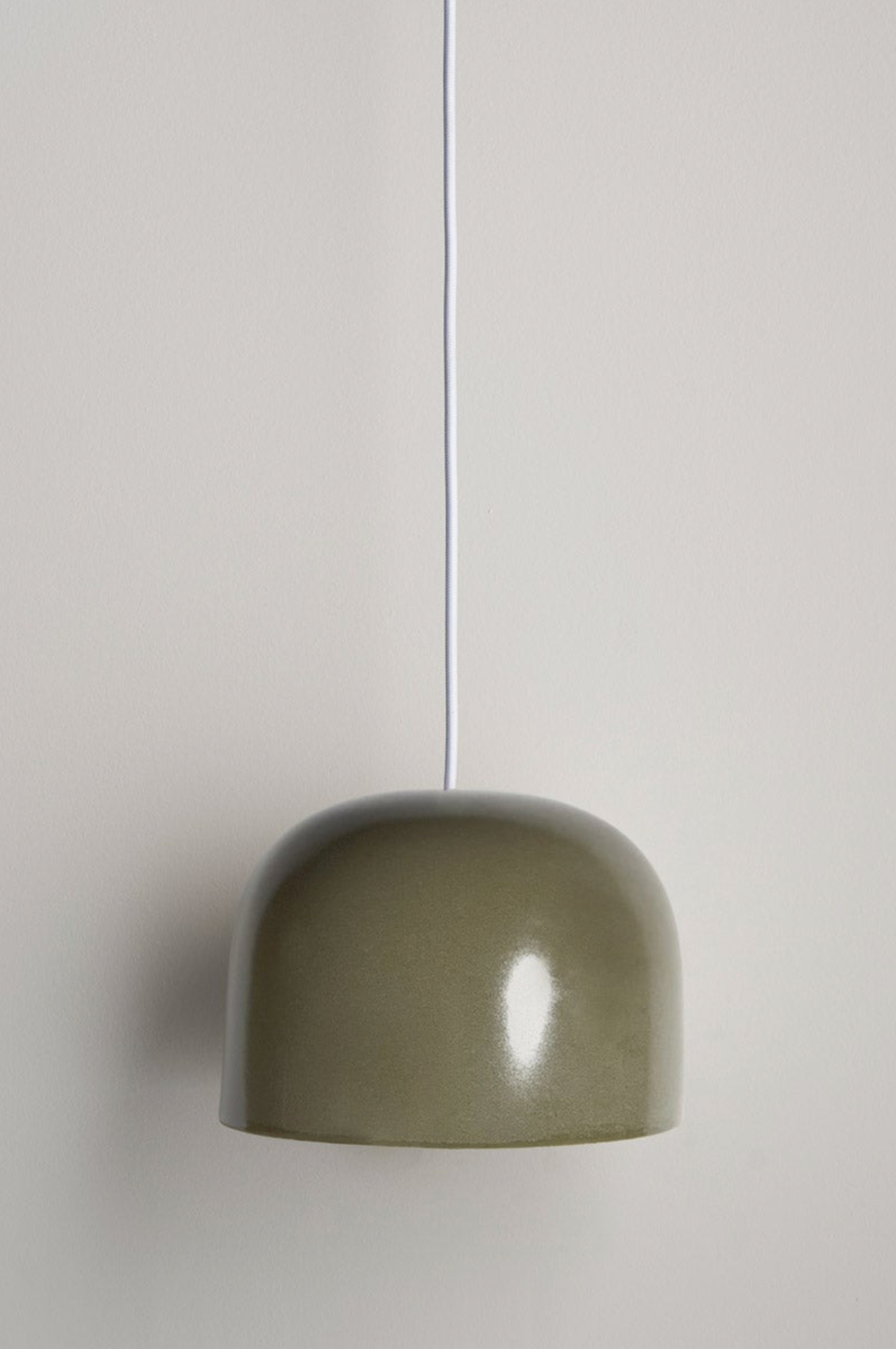 Green ceramic pendant light against a plain background