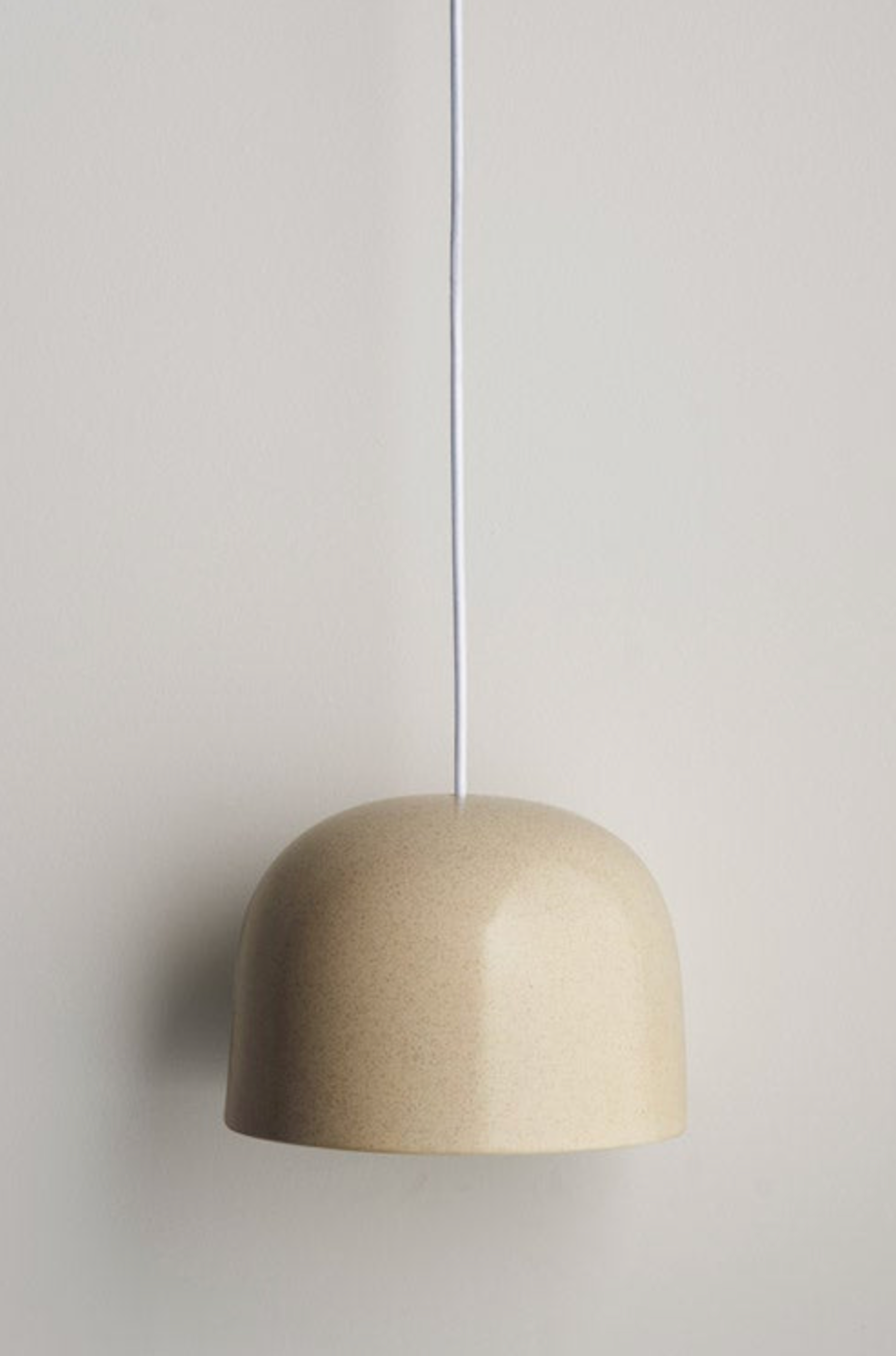 Beige ceramic interior pendant light against a plain wall
