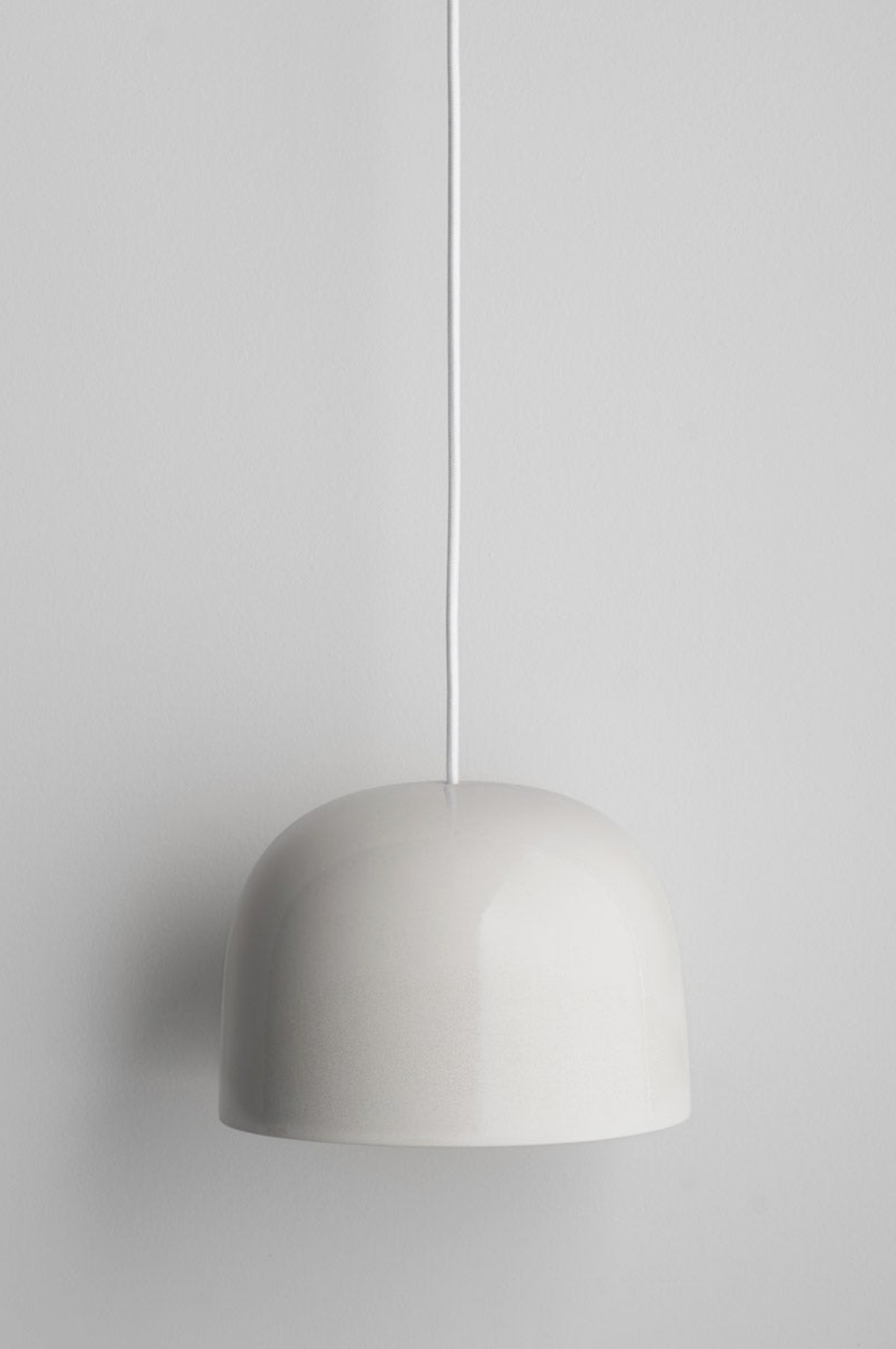 Minimalist ceramic pendant light on a plain grey background