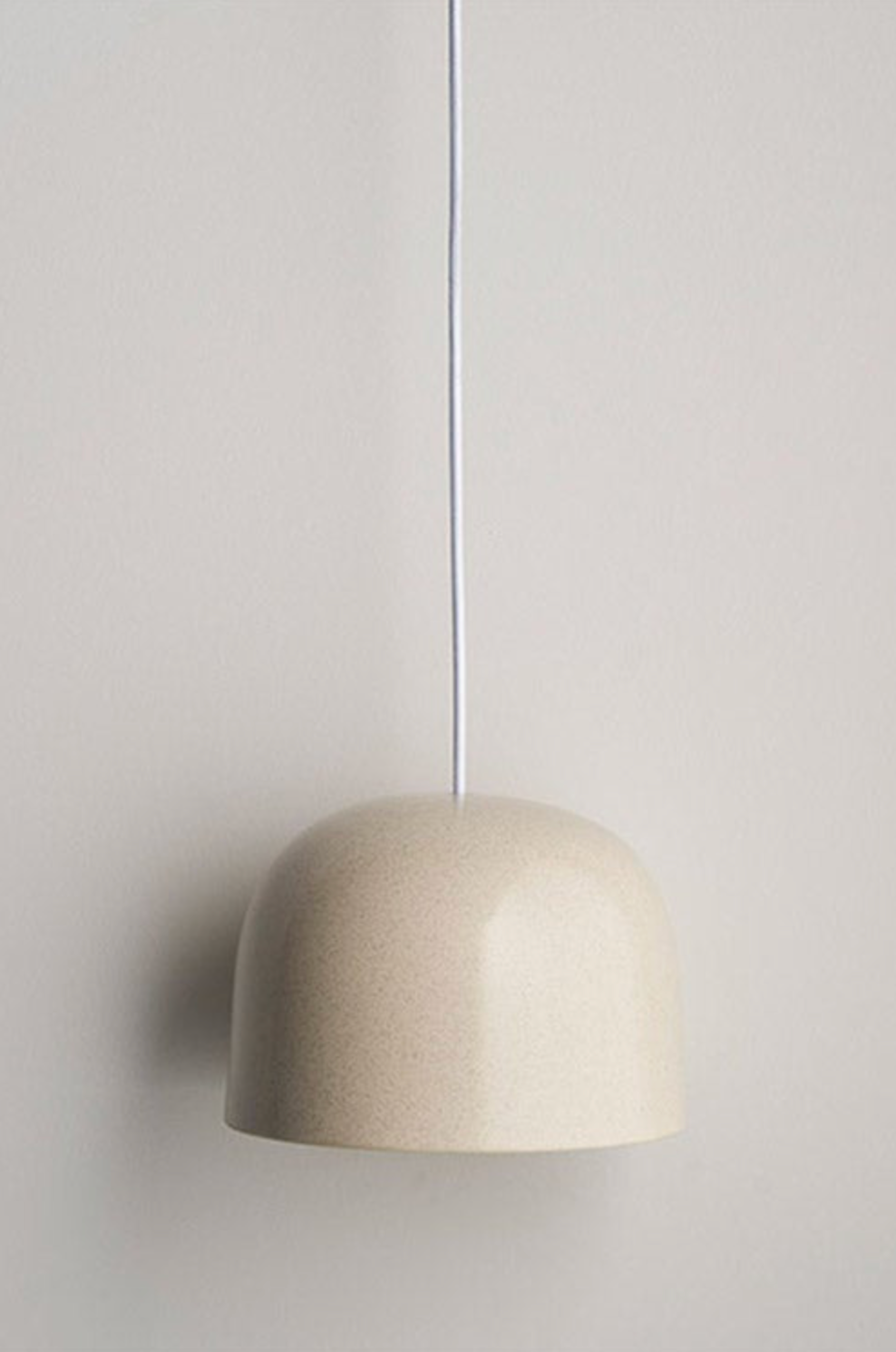 Beige ceramic pendant light against a plain wall