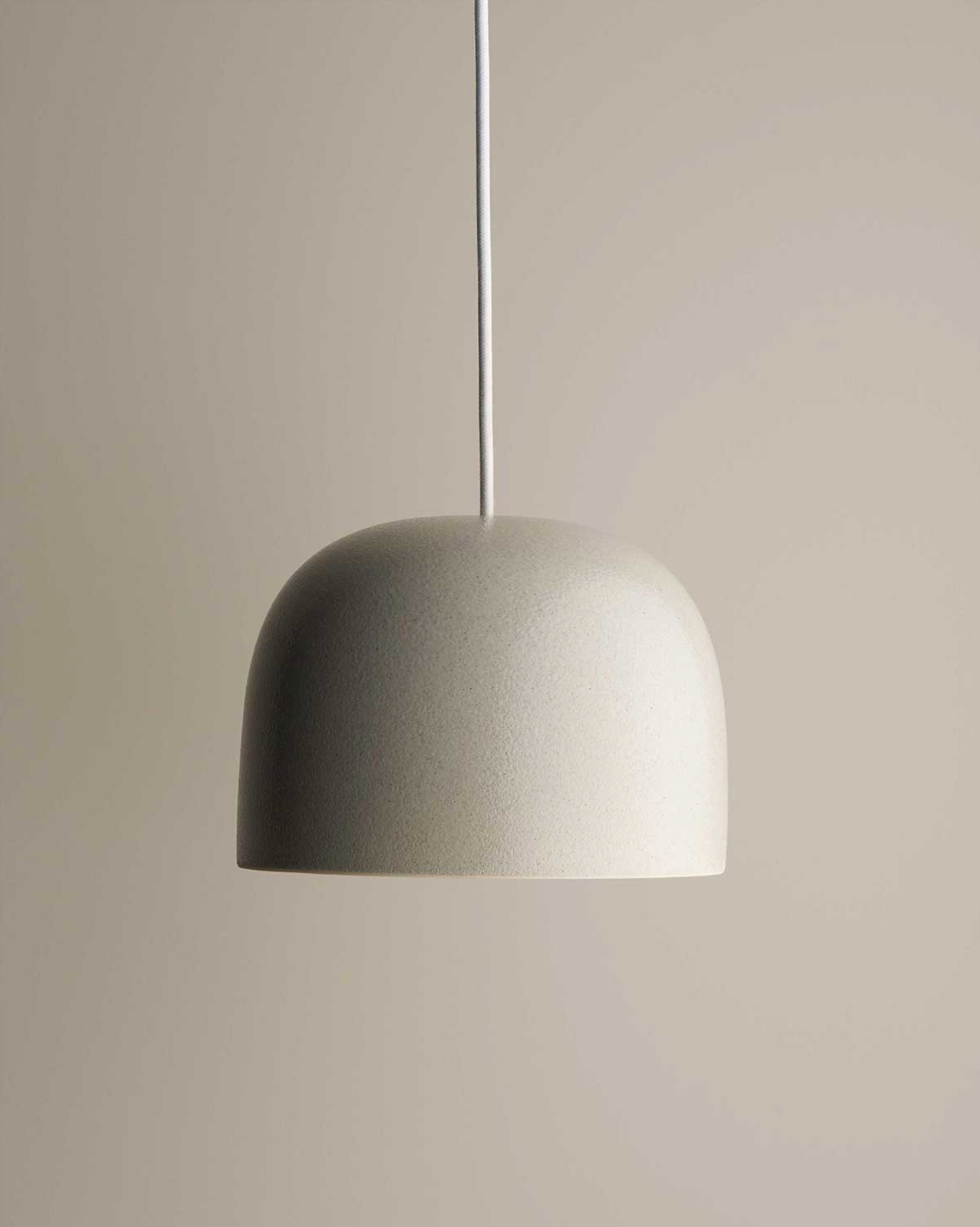 Grey textured ceramic pendant light against a neutral background