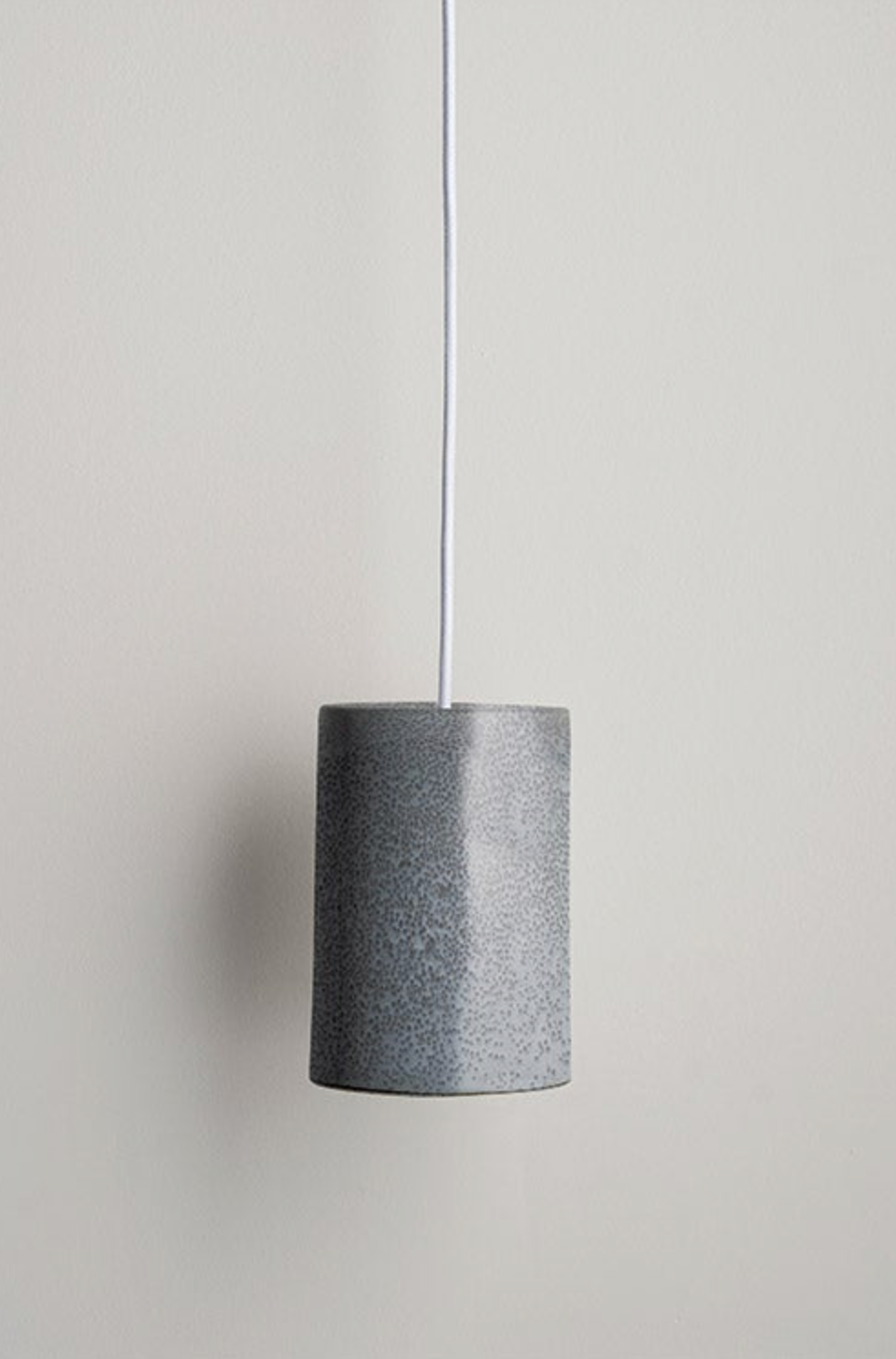 Textured ceramic cylindrical pendant light on a neutral background