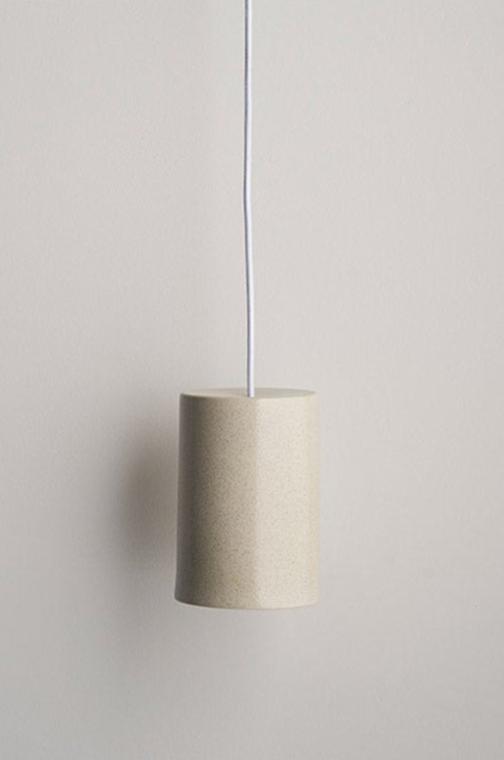 Beige ceramic interior pendant lamp hanging against a plain wall