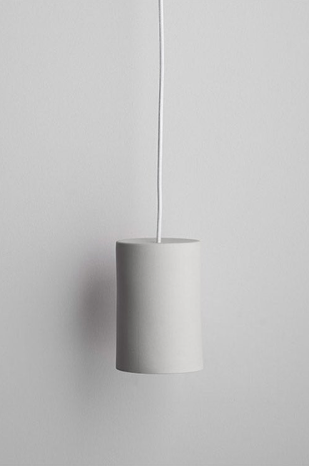 Minimalist ceramic pendant light against a plain background