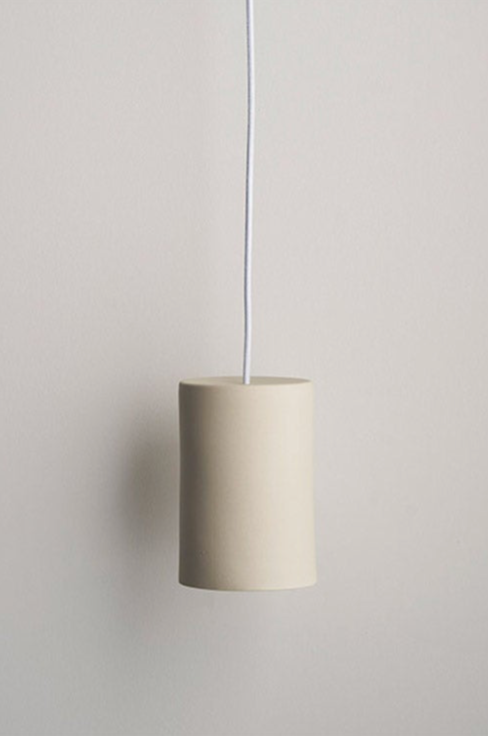 Beige ceramic pendant light hanging against a plain wall