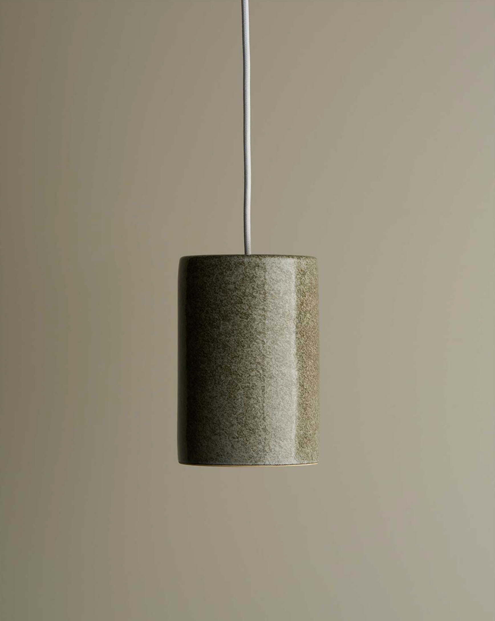 Cylindrical ceramic interior pendant light with textured finish on a neutral background