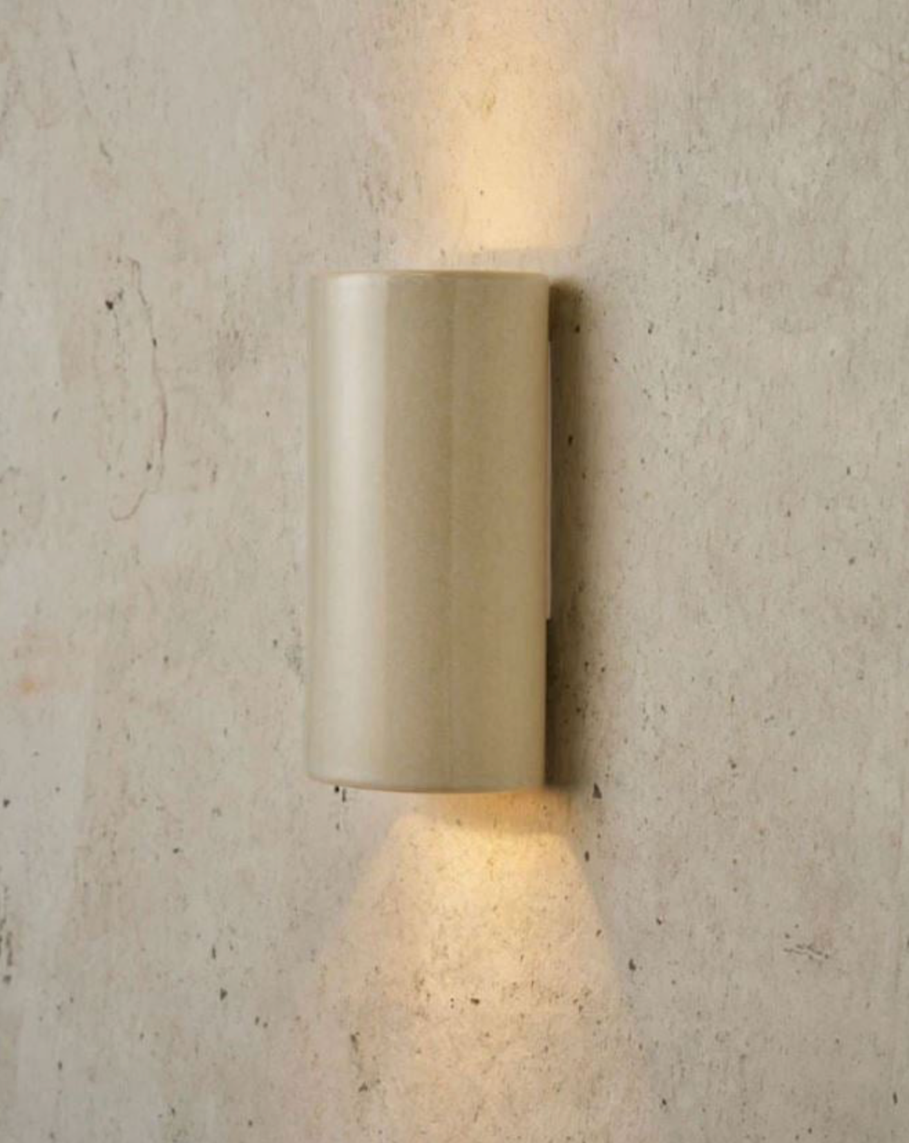 Beige ceramic wall-mounted light fixture on a textured concrete wall
