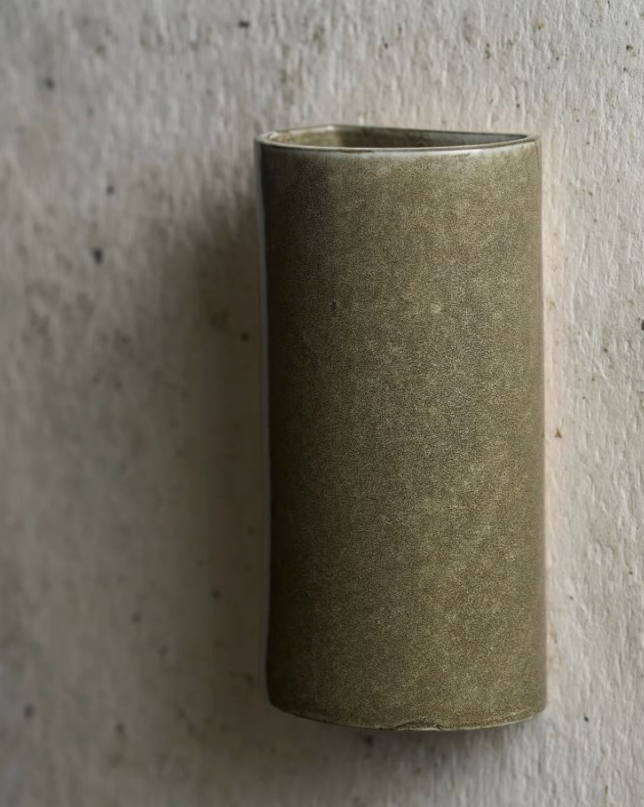 Cylindrical ceramic interior wall light on a textured grey background